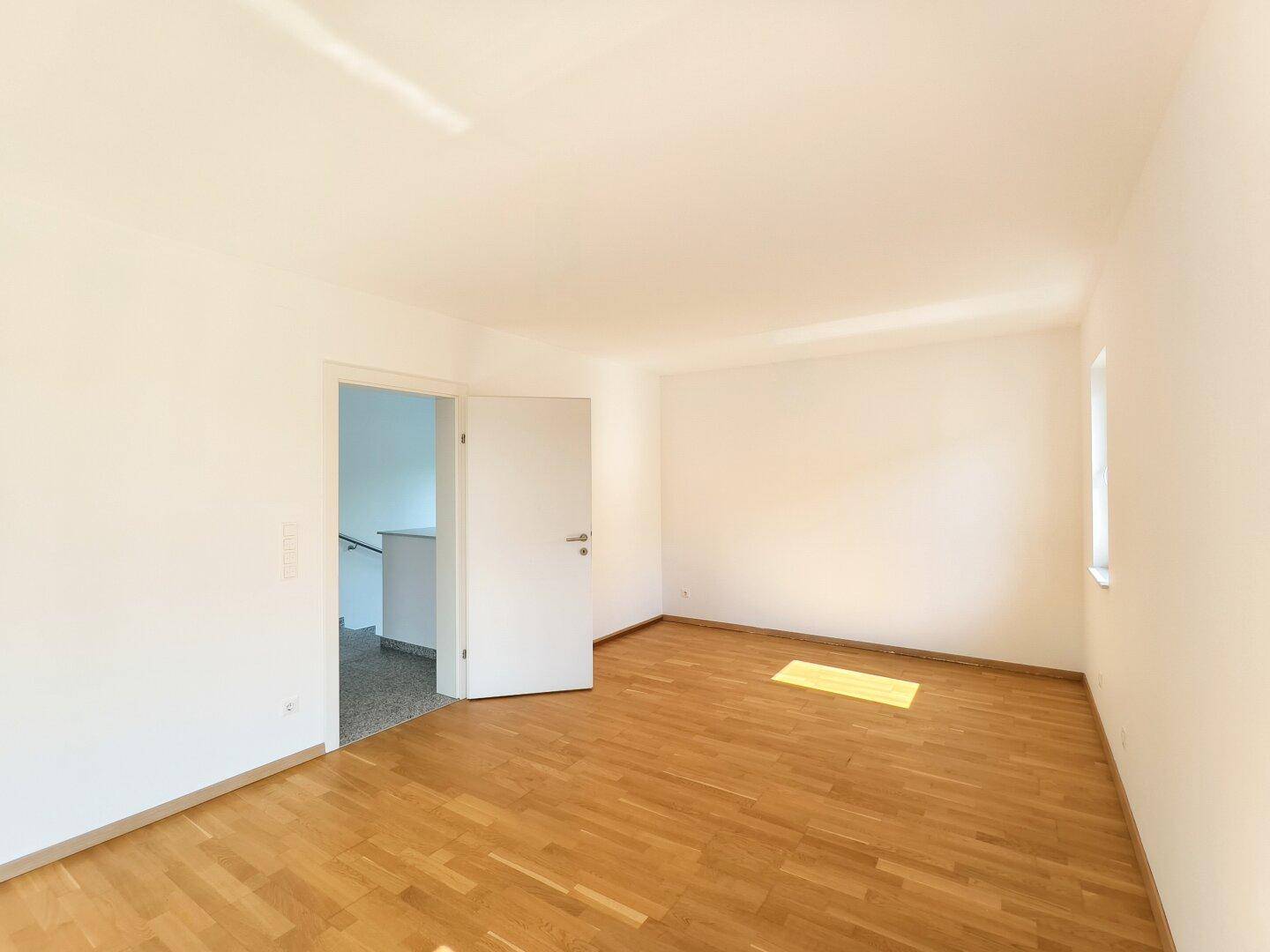 Schlafzimmer mit Holzboden und weiß gestrichenen Wänden, bereit zur individuellen Gestaltung.