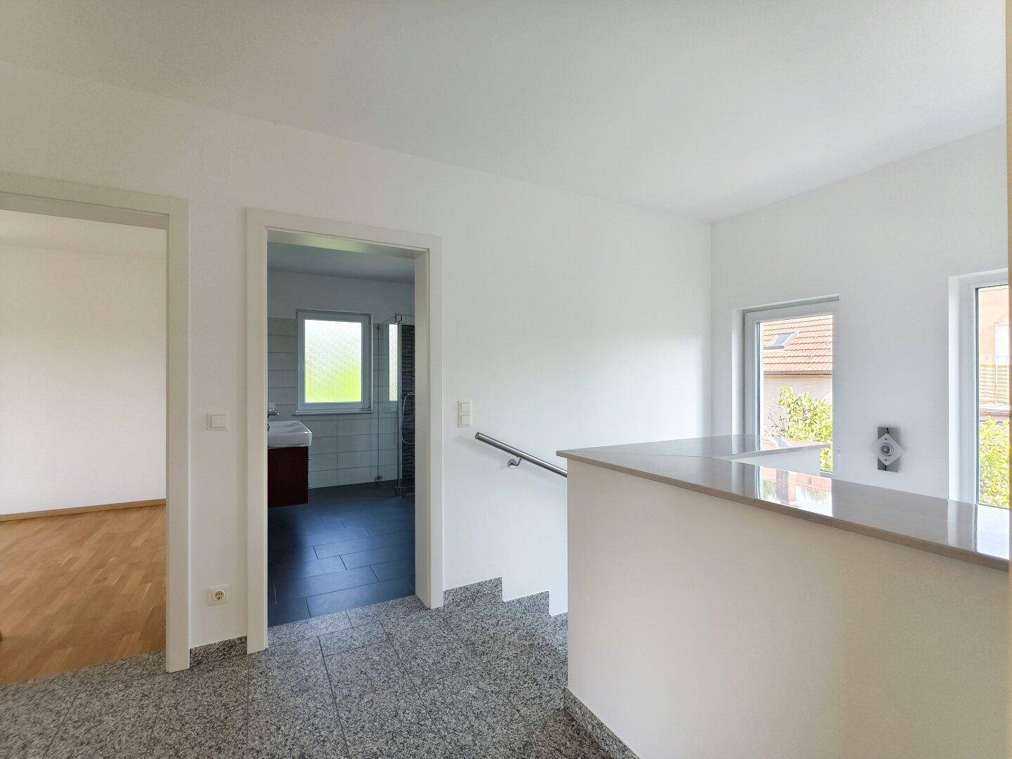 Heller Flur mit Granitboden und Treppe, die zu weiteren Räumen führt.