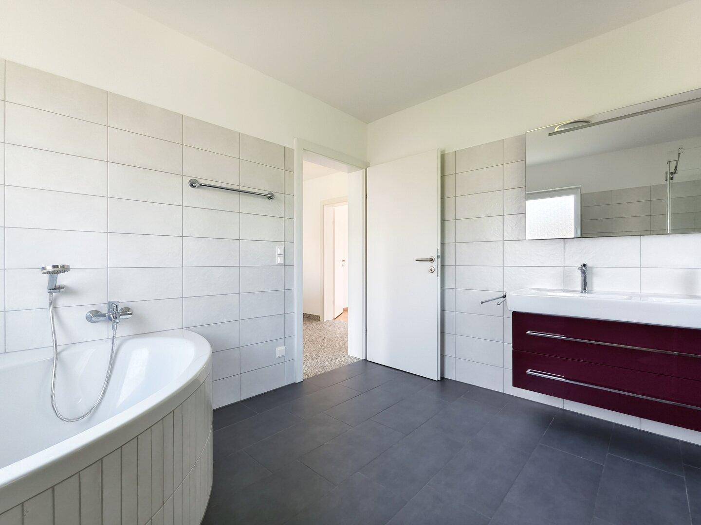 Modernes Badezimmer mit Badewanne, Doppelwaschbecken und großem Spiegel.