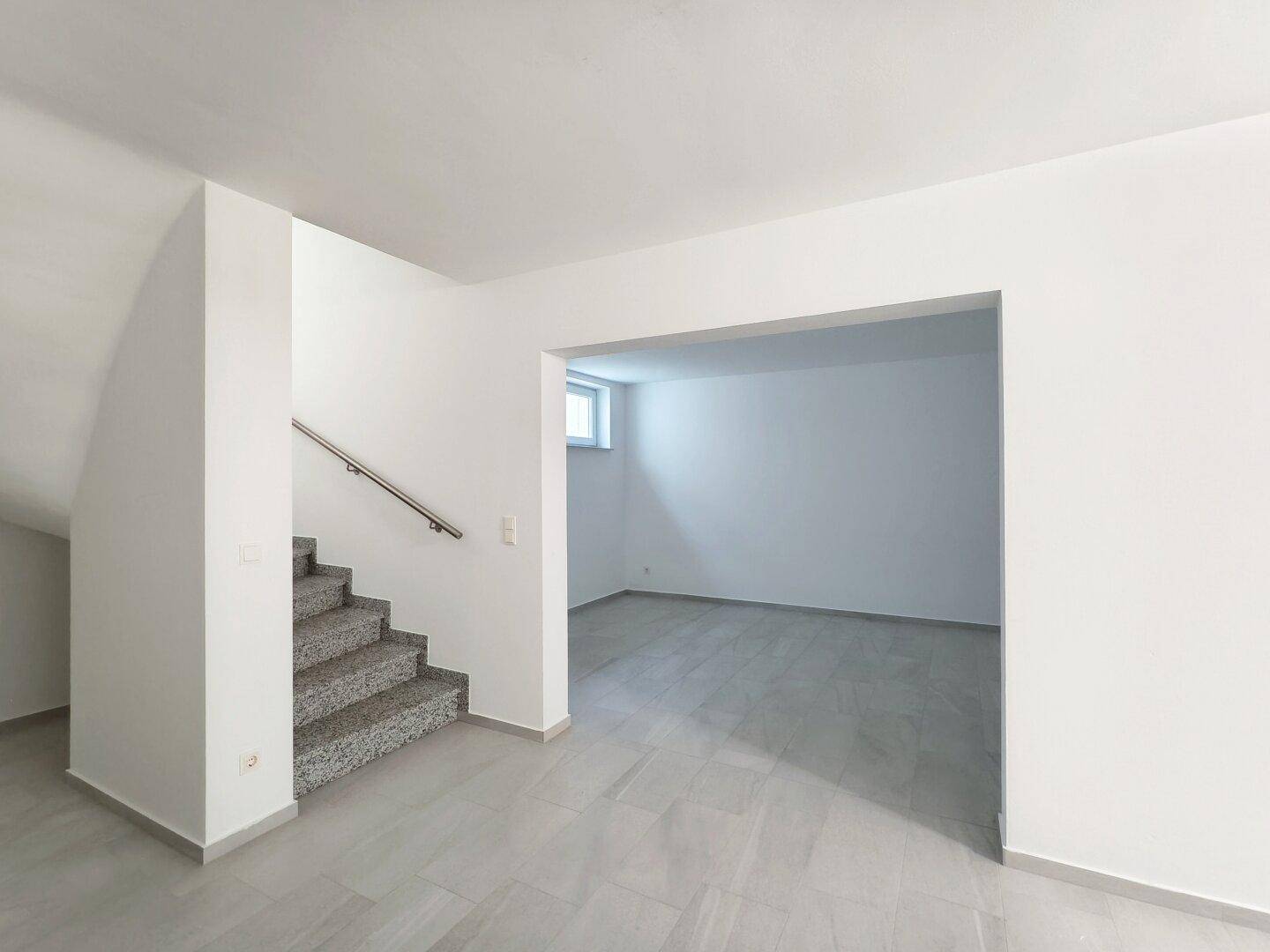 Heller Kellerraum mit Fliesenboden und Zugang über eine Granittreppe.