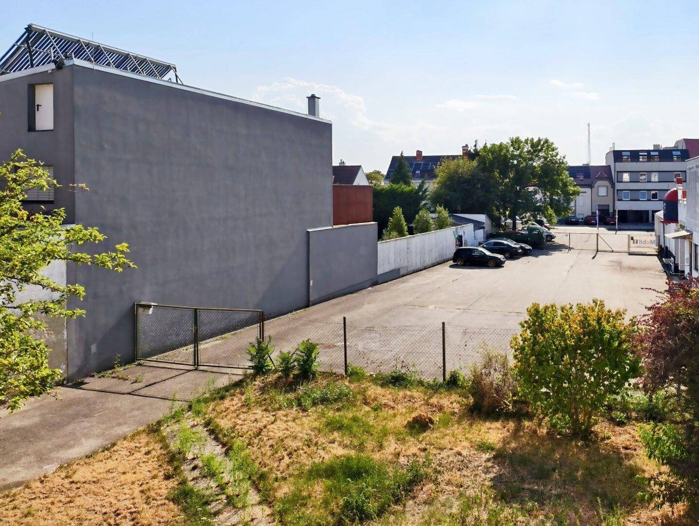 Außenansicht eines Gebäudes mit großem Parkplatz und umliegender Bebauung.
