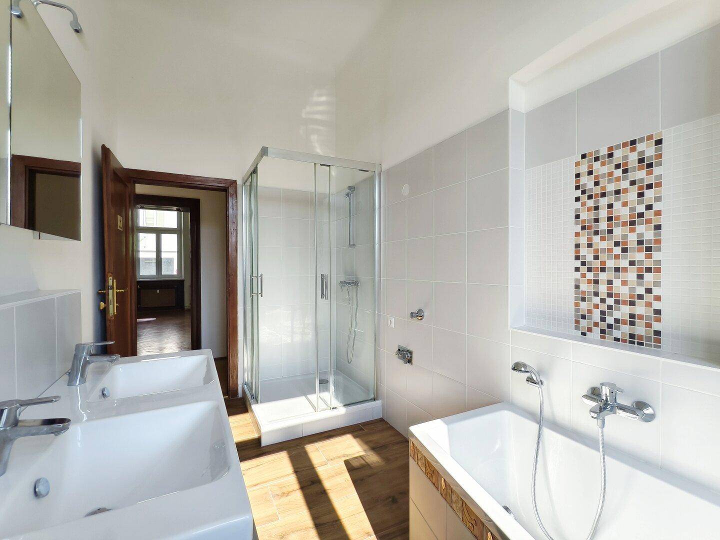 Helles Badezimmer mit Duschkabine, Badewanne und Doppelwaschbecken.