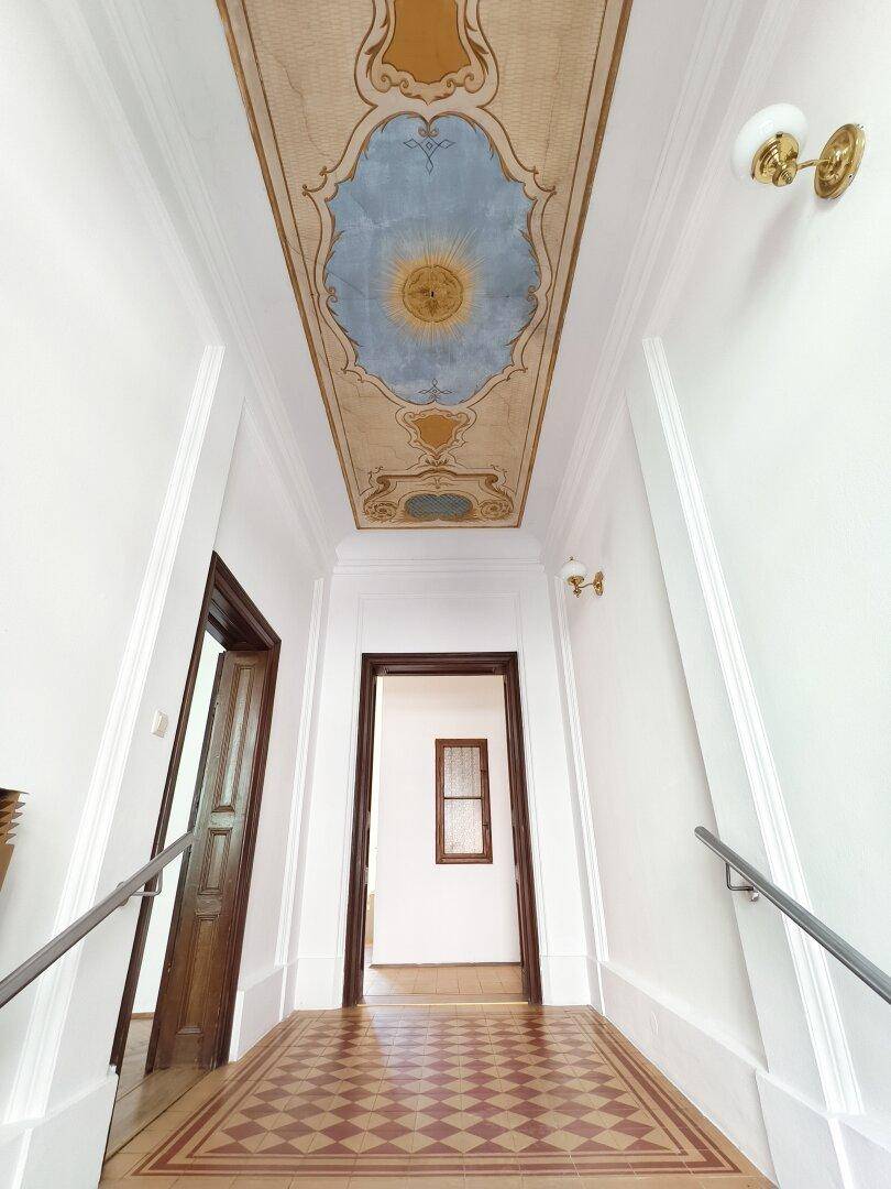 Eleganter Flur mit kunstvoll bemalter Decke, Schachbrettmuster-Boden und Holztüren.