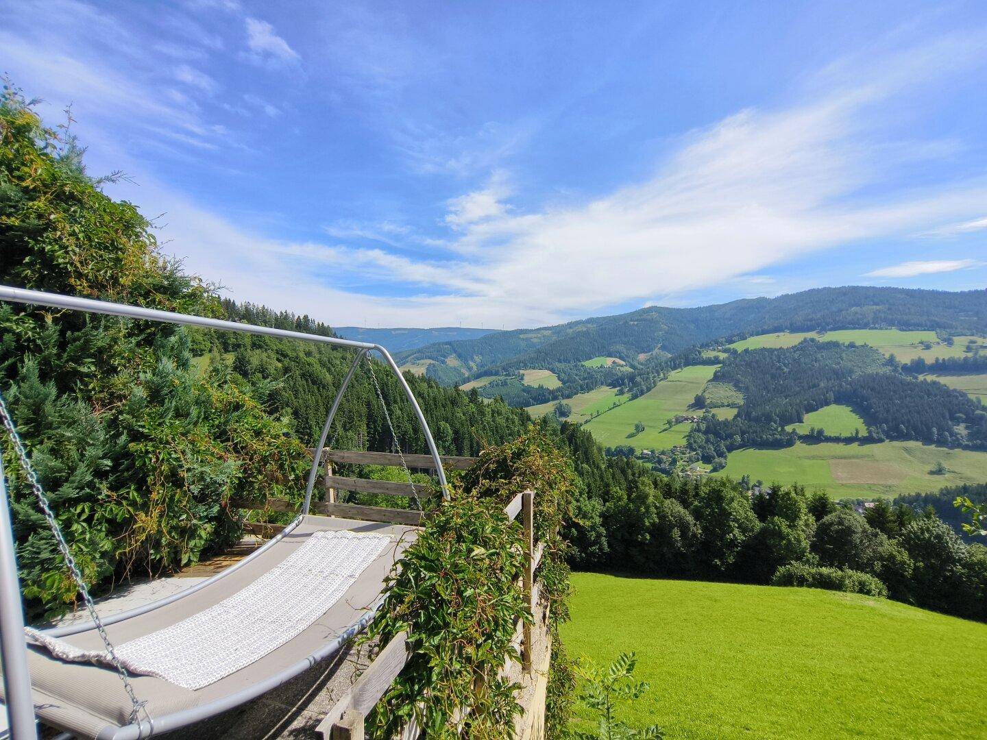 Entspannungsbereich im Freien mit Schaukel und weitem Blick über die malerische Hügellandschaft.