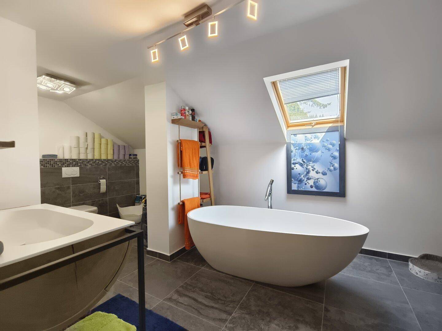 Modernes Badezimmer im Dachgeschoss mit freistehender Badewanne und Dachfenster.