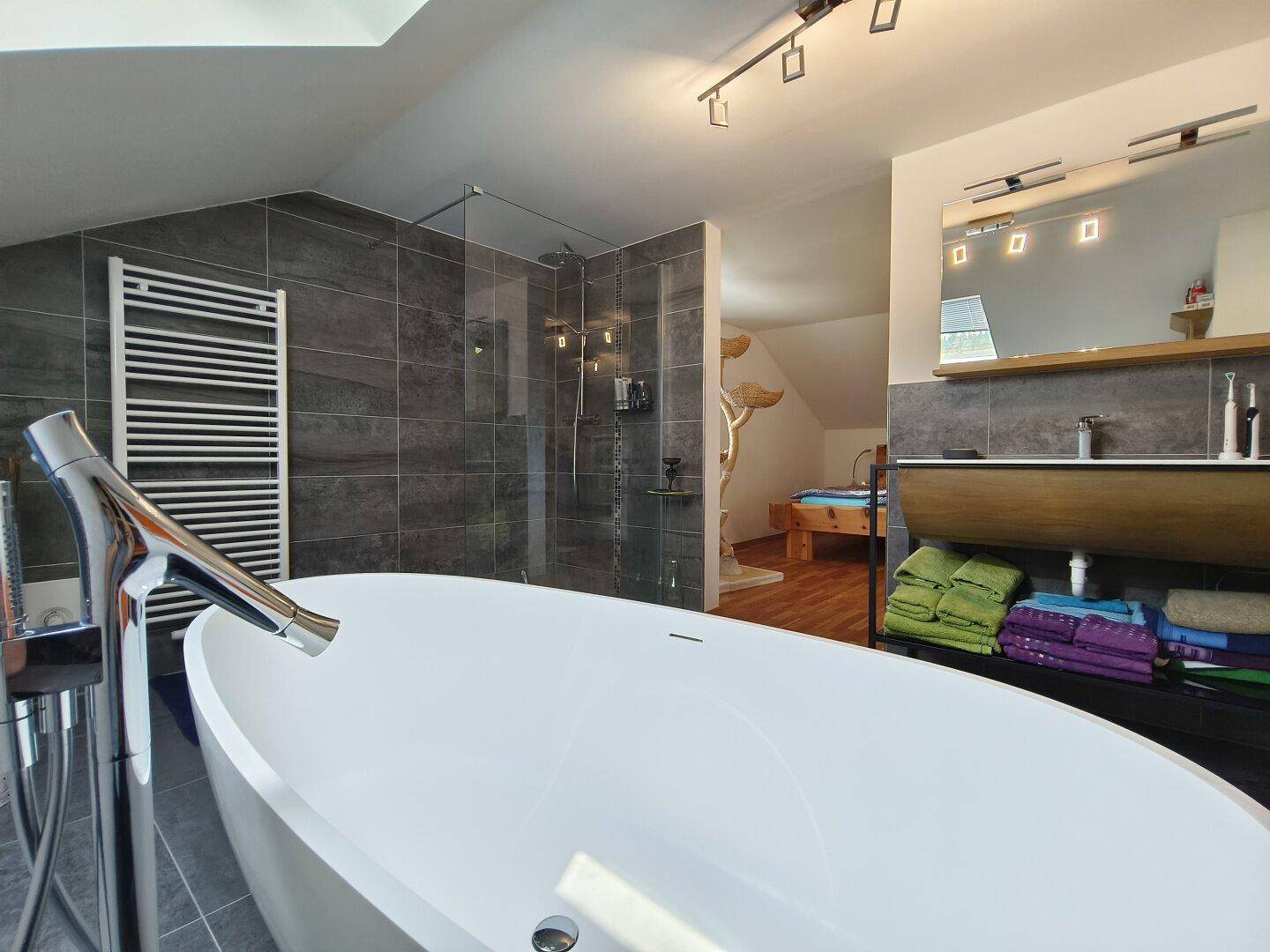 Elegantes Badezimmer mit freistehender Badewanne, großer Dusche und modernem Waschtisch.