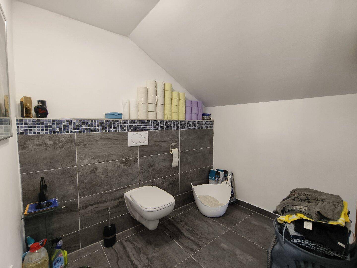 Separate Toilette im Dachgeschoss mit Wand-WC und Fliesenboden.