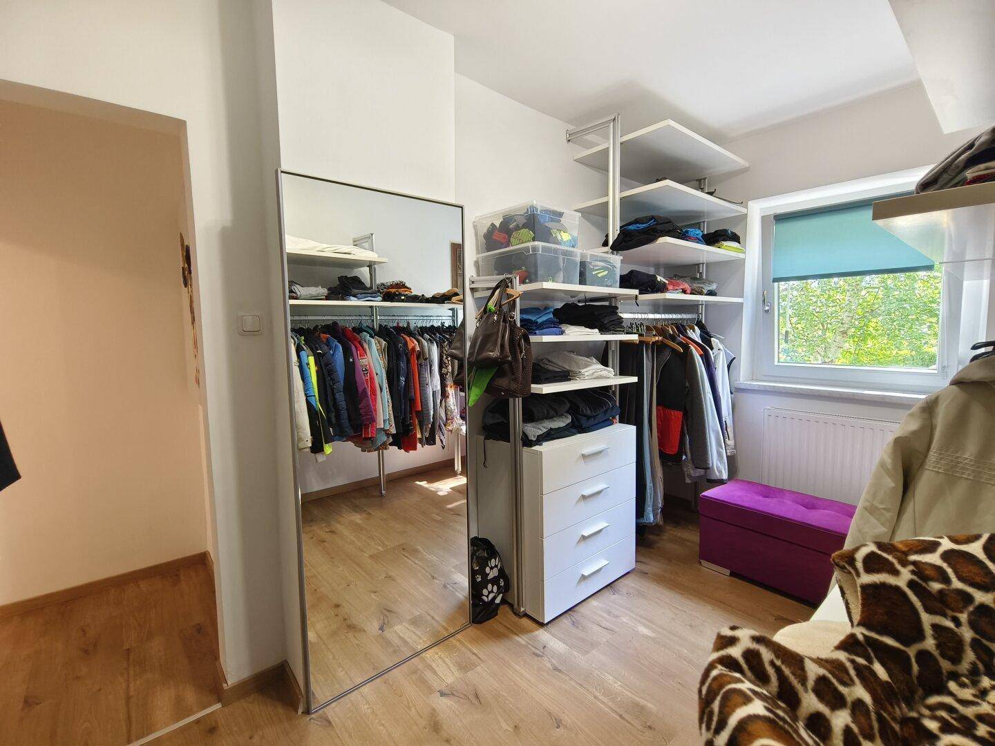 Begehbarer Kleiderschrank mit Regalsystemen, Kleiderstangen und großem Spiegel.
