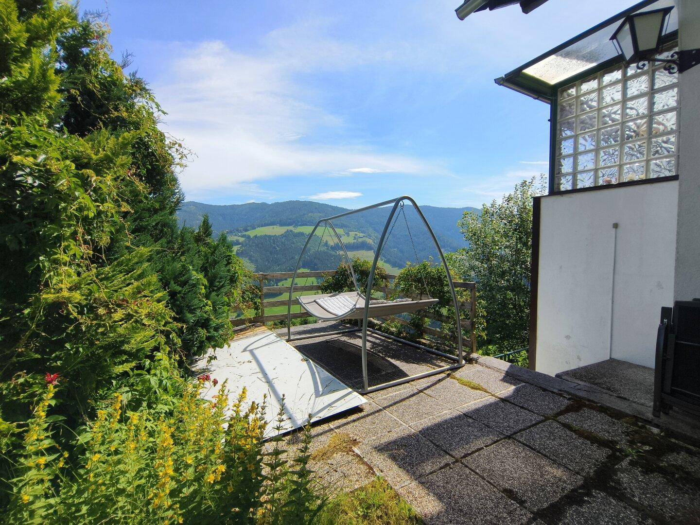 Geräumige Terrasse mit Schaukel und weitem Blick über das Tal, direkt am Haus gelegen.