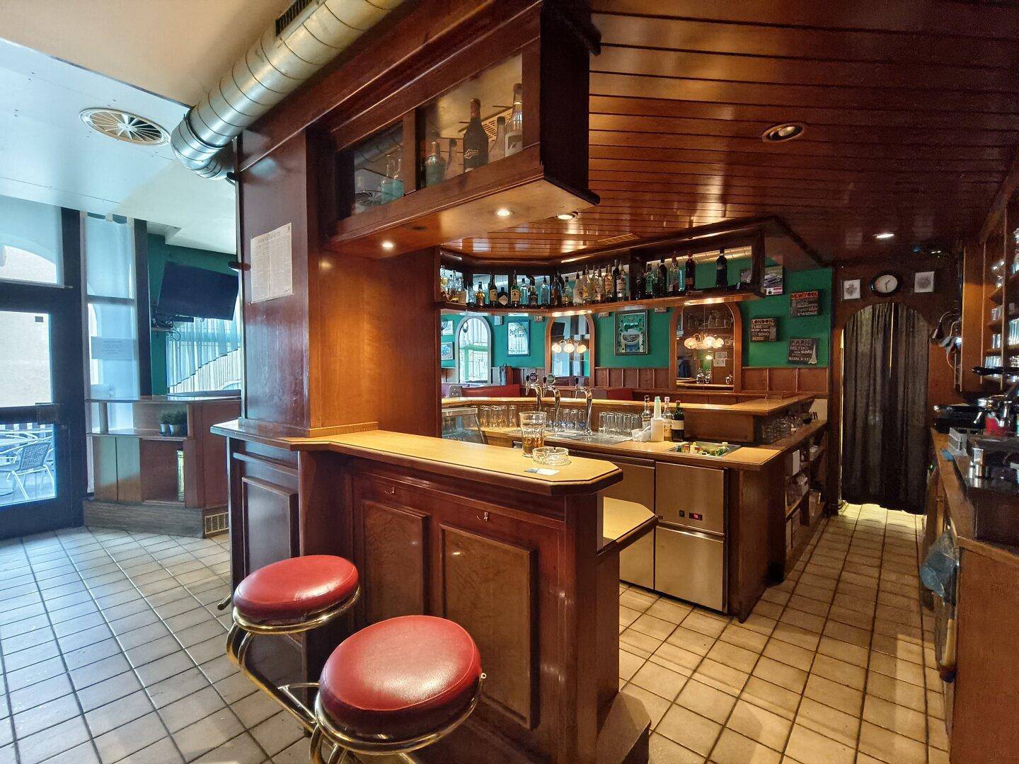 Detailansicht der Bar mit Zapfanlage, Hockern und Blick auf den Außenbereich durch die Tür.