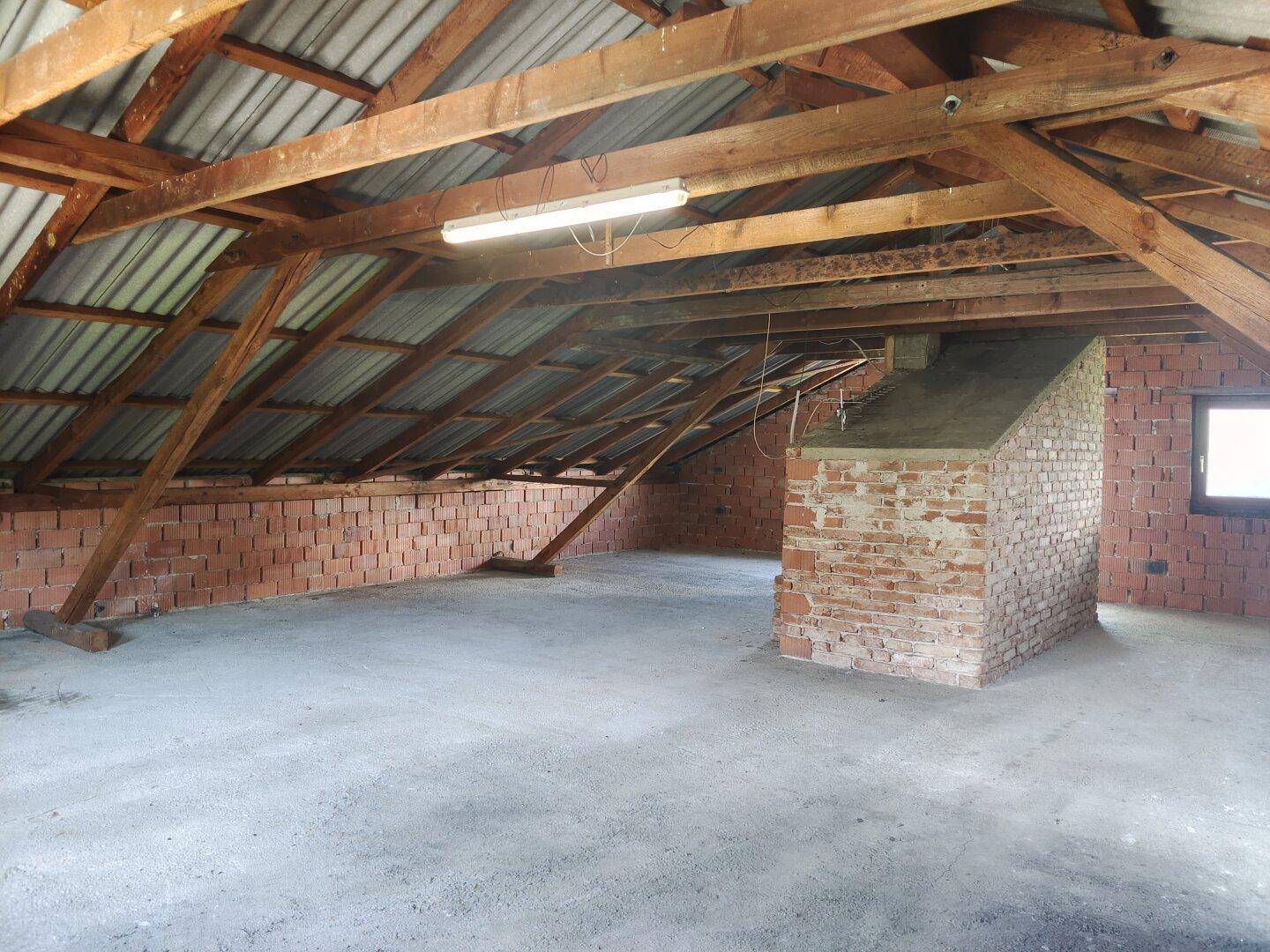 Großer Dachbodenbereich mit offener Holzkonstruktion und Ziegelwänden, ideal für Lagerung.