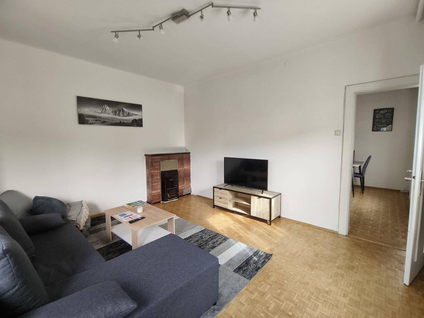 Gemütliches Wohnzimmer mit Parkettboden, einem Kamin und einem bequemen Sofa.