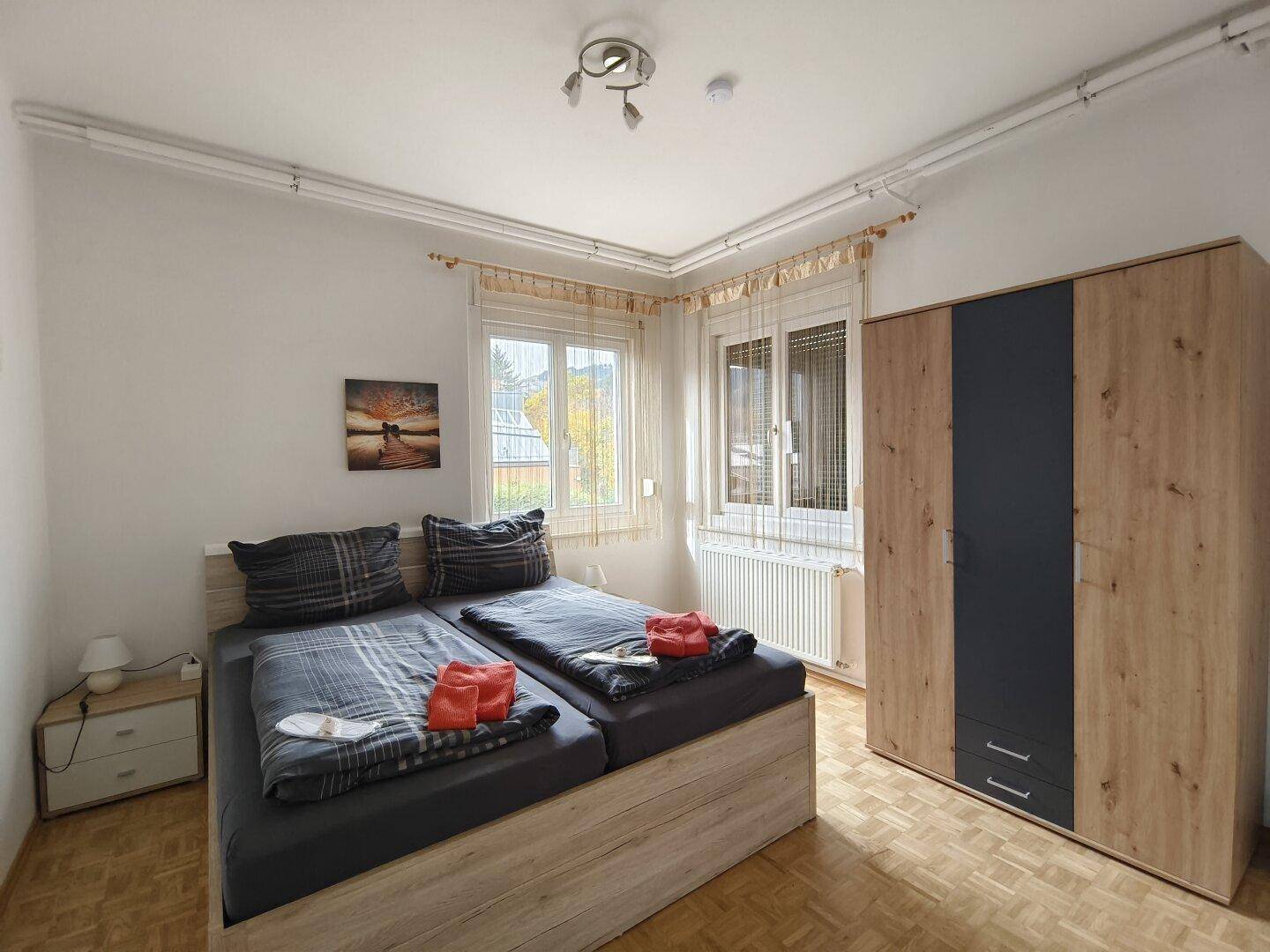 Schlafzimmer mit zwei Einzelbetten, einem Kleiderschrank und Parkettboden.