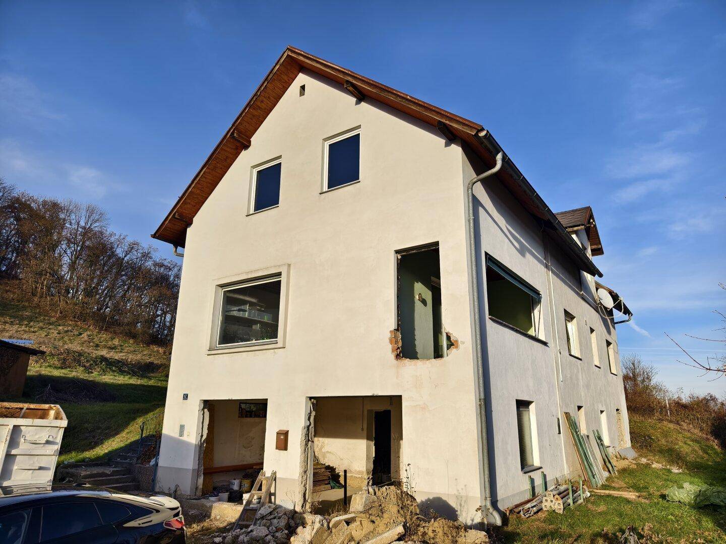 Außenansicht eines Hauses in Sanierungszustand mit sichtbaren Umbauarbeiten und fehlenden Fenstern.
