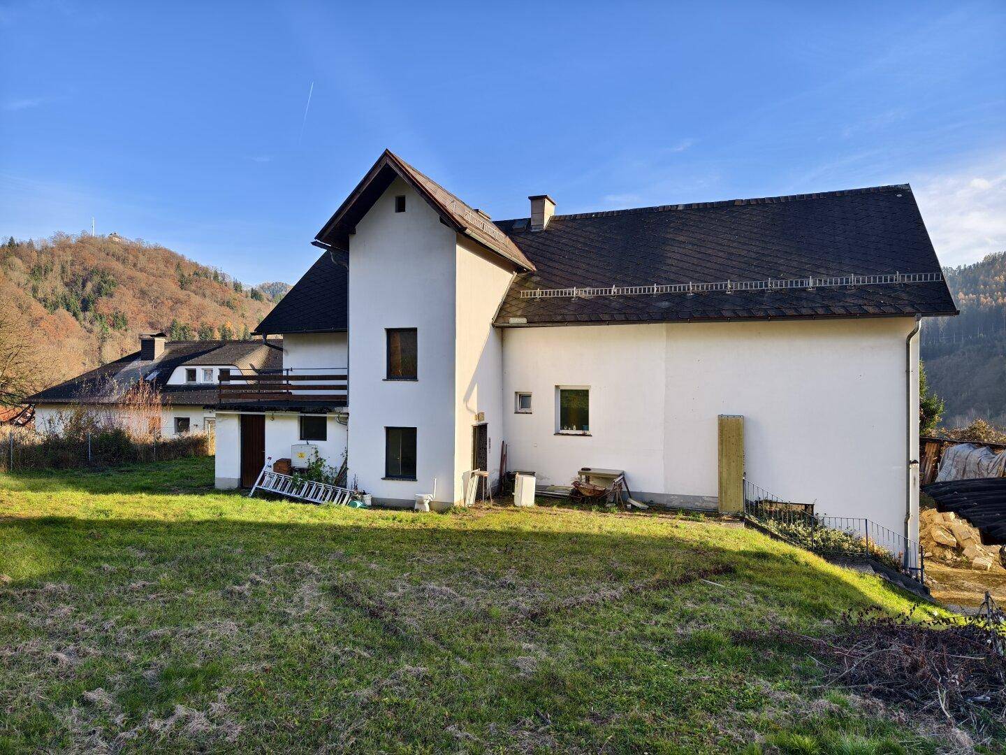 Rückansicht eines Hauses mit großem grünen Garten und Blick auf die umliegende Landschaft.