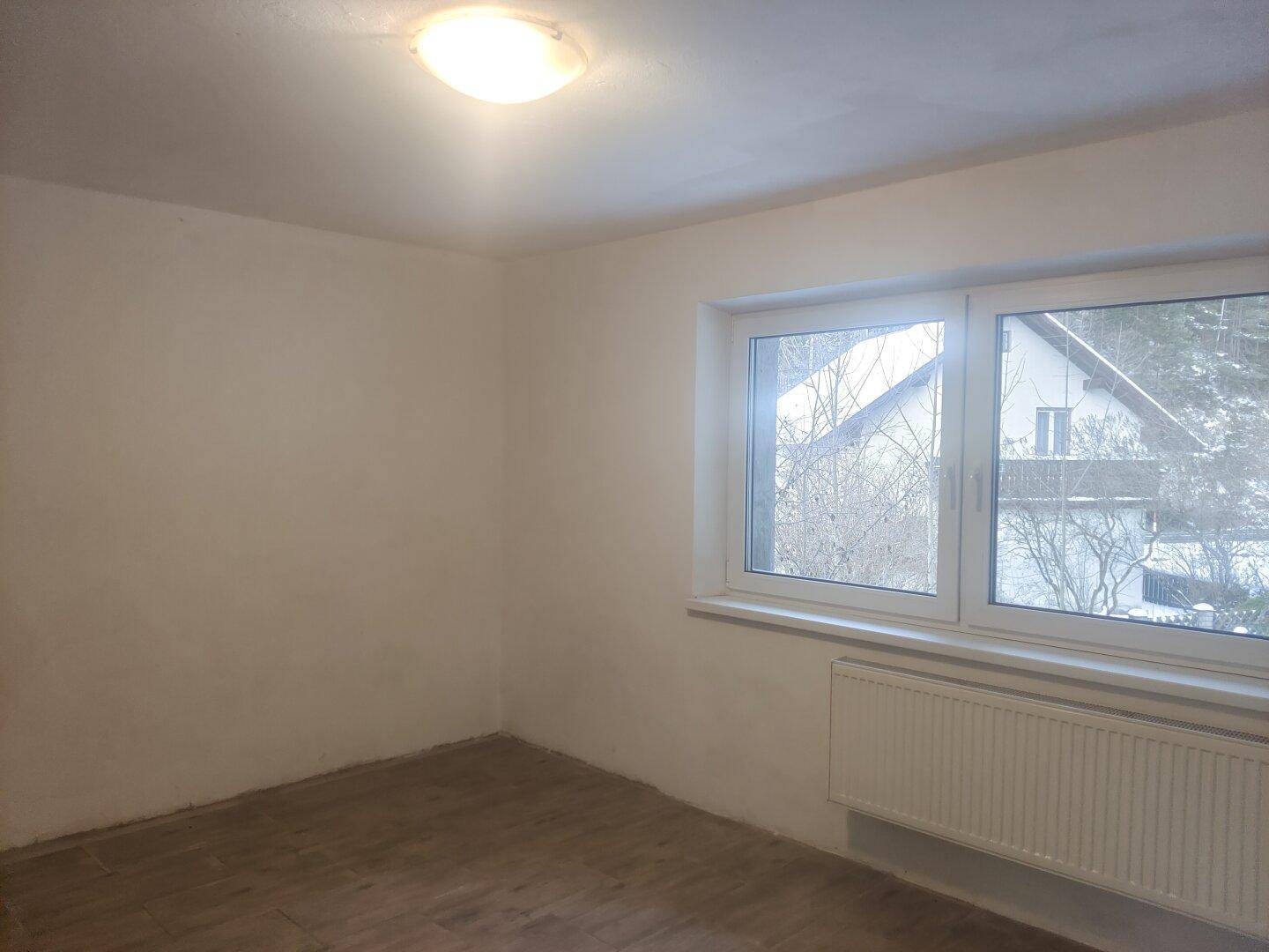 Helles Zimmer mit Fenster und Blick auf die verschneite Umgebung, bereit zur Einrichtung.