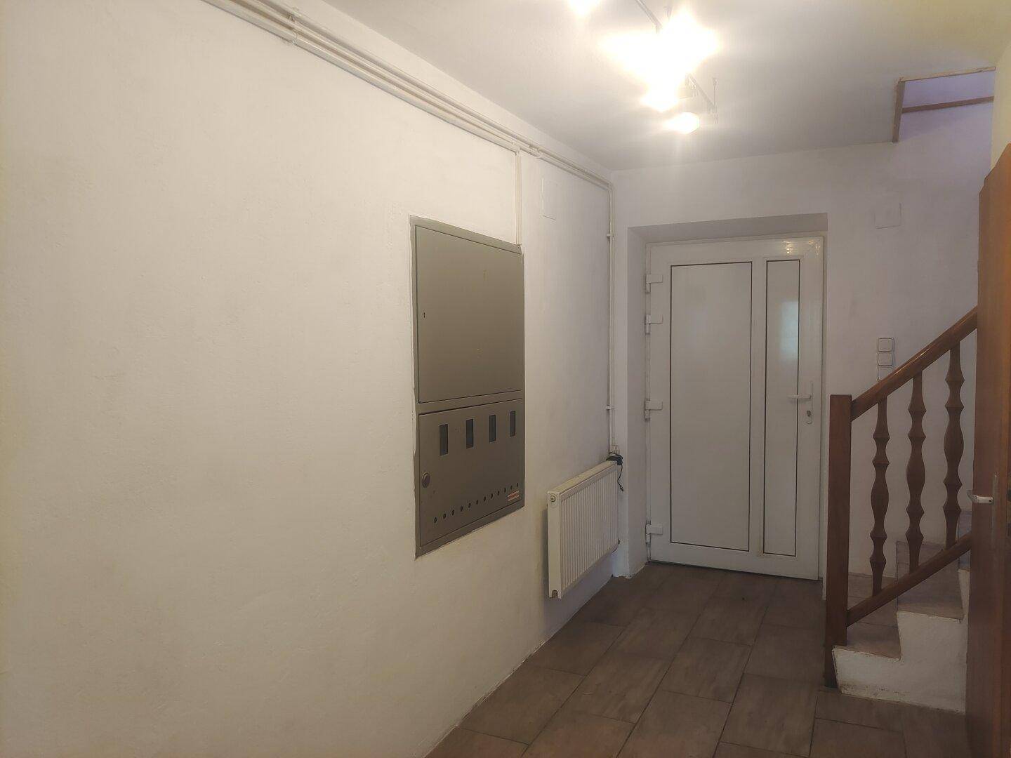 Eingangsbereich mit Fliesenboden, Treppe und Sicherungskasten an der Wand.