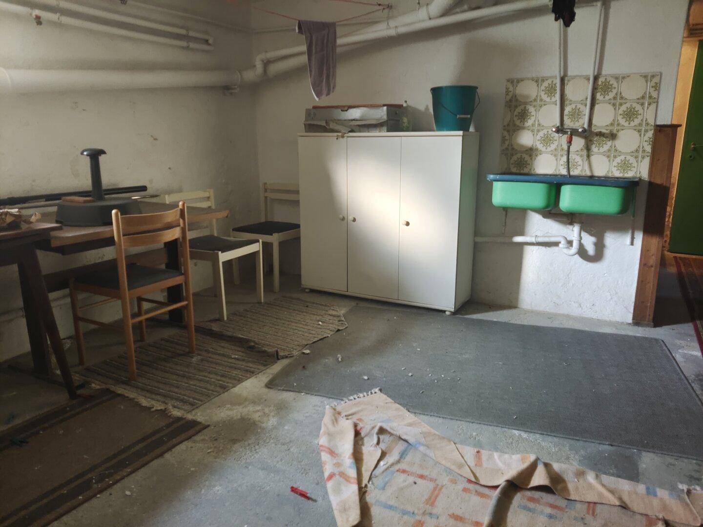 Kellerraum mit Waschbecken, Schrank und einfacher Ausstattung, ideal als Abstellraum.