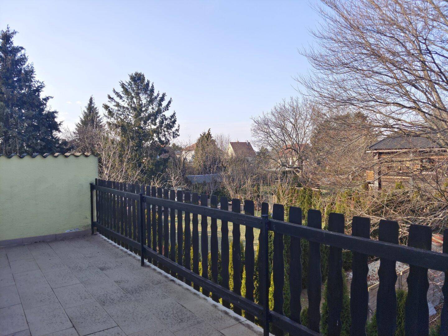 Geräumiger Balkon mit Holzzaun und weitem Blick über die umliegende Landschaft.