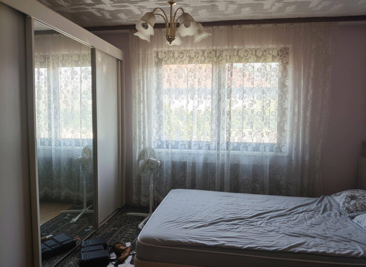 Schlafzimmer mit großem Spiegelschrank, Doppelbett und viel Tageslicht durch die Fenster.