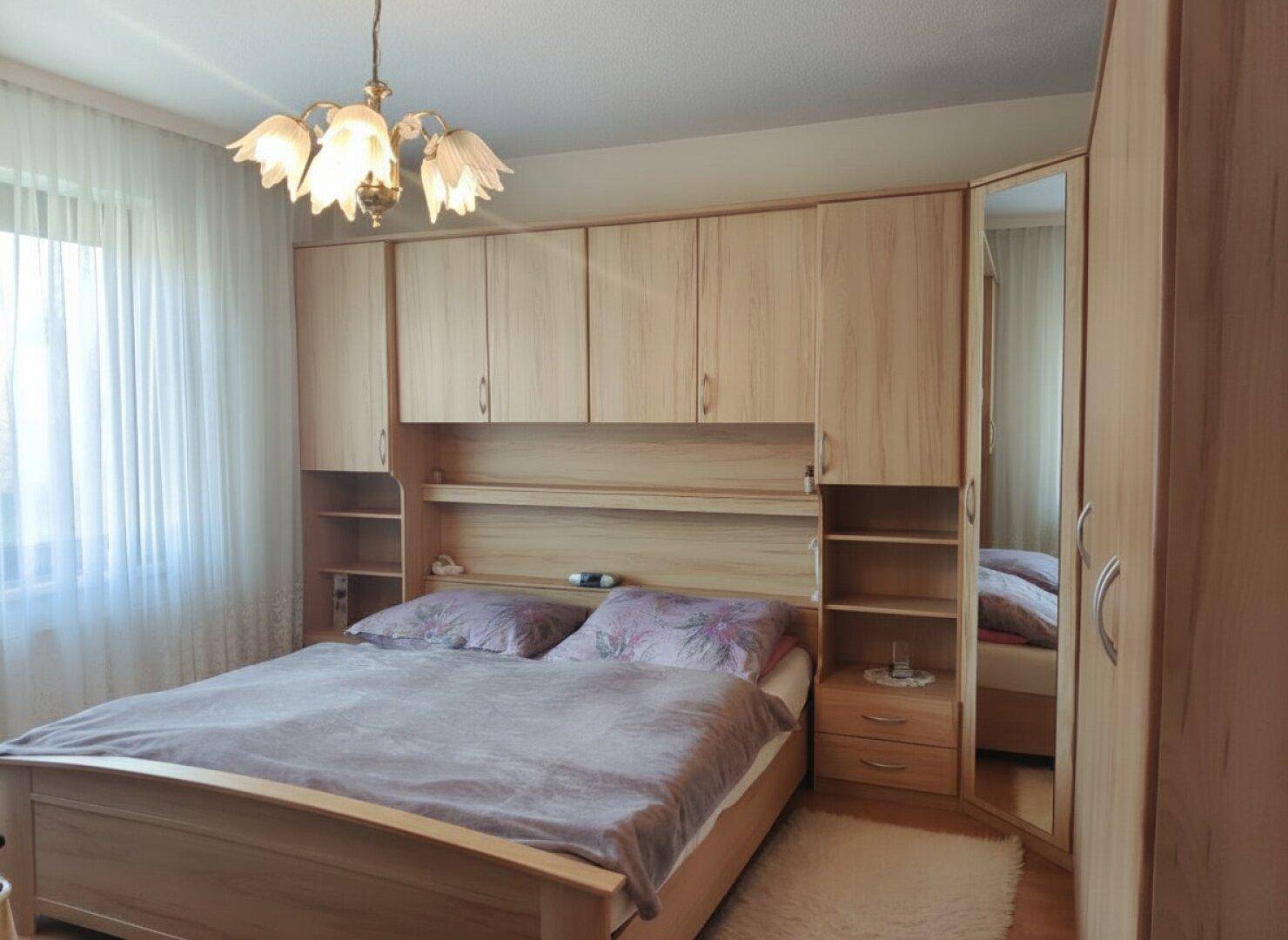 Schlafzimmer mit Doppelbett und praktischen Einbauschränken über dem Bett für Stauraum.