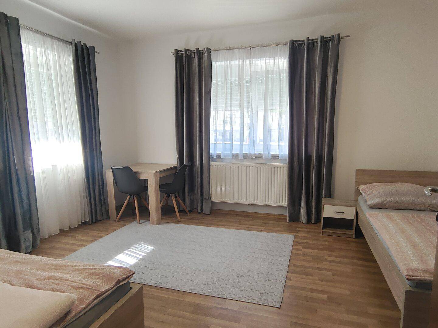 Geräumiges Schlafzimmer mit Holzboden, zwei Einzelbetten und einem kleinen Esstisch.