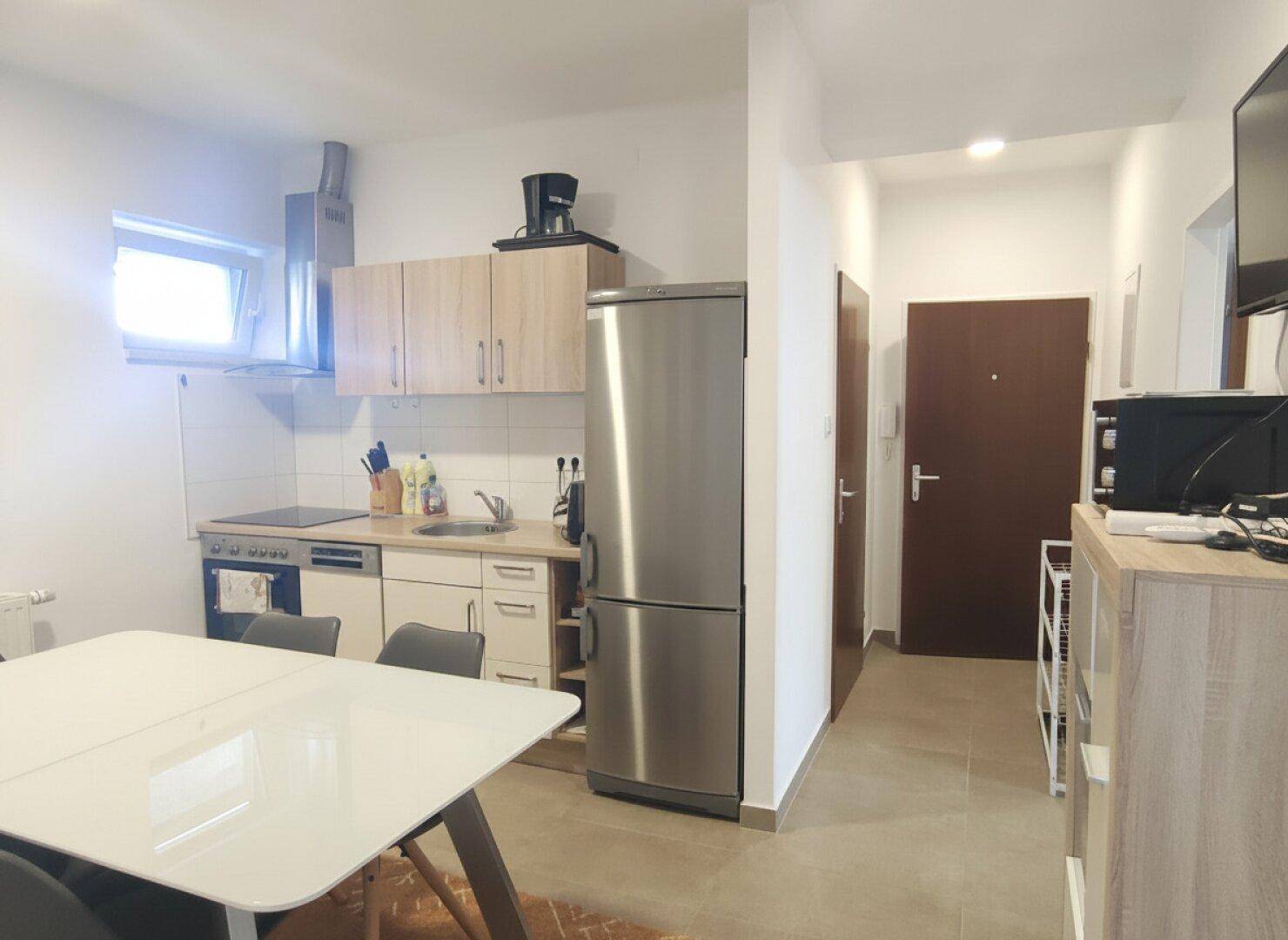 Kleine Küche mit Essbereich, modernen Holzschränken und Edelstahlgeräten.