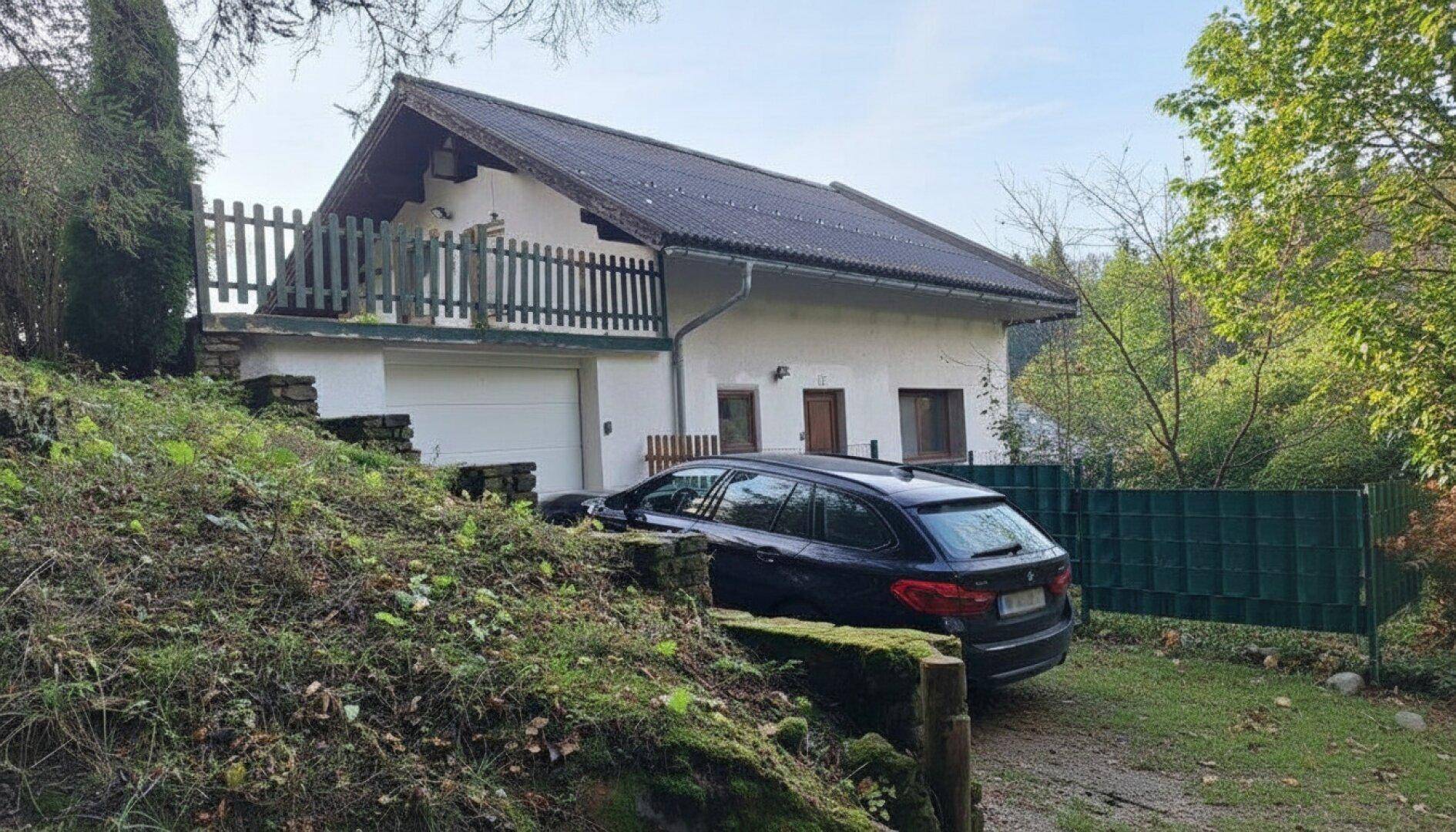 Einfamilienhaus mit Satteldach, Garage und umgebender Natur.