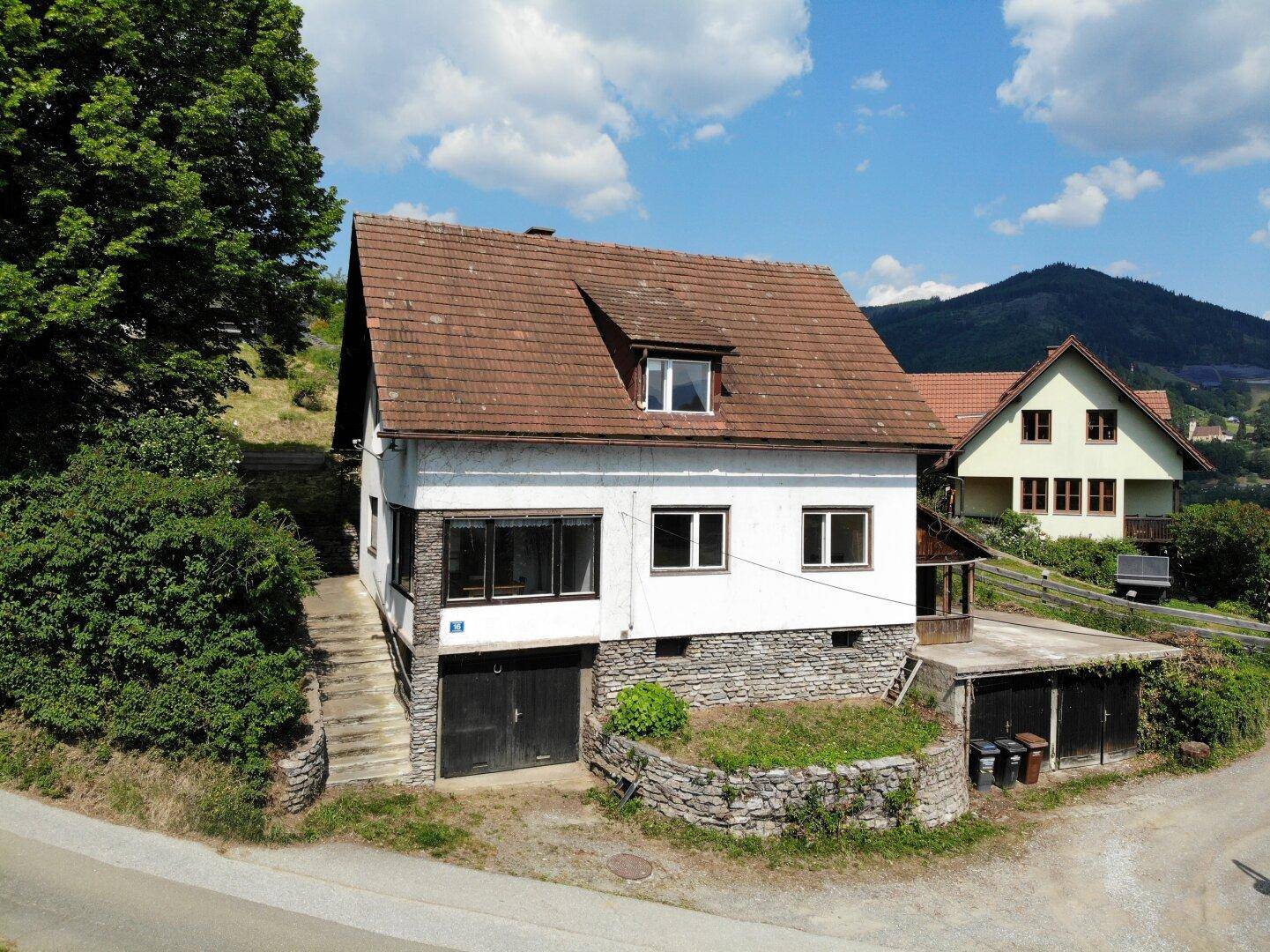 Vorderansicht des Hauses mit Steinfassade im unteren Bereich und Satteldach.