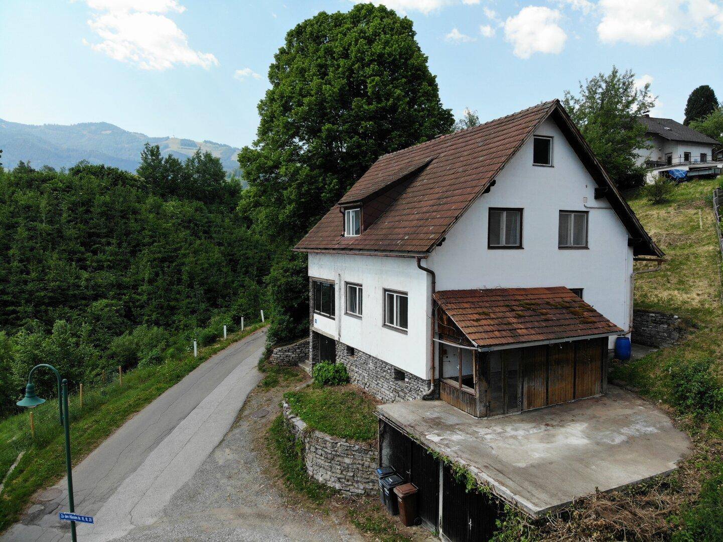 Seitenansicht des Hauses mit Holzanbau und Blick auf die umliegende Natur.