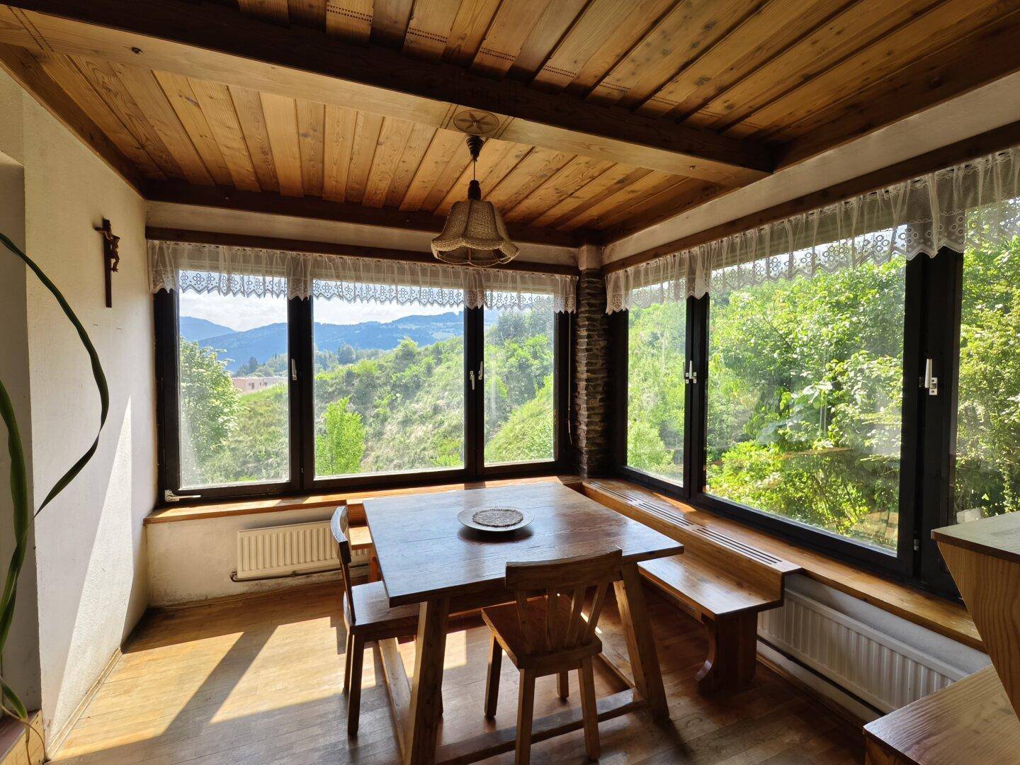 Gemütlicher Essbereich mit Holztisch, Bänken und weitem Blick in die Natur.