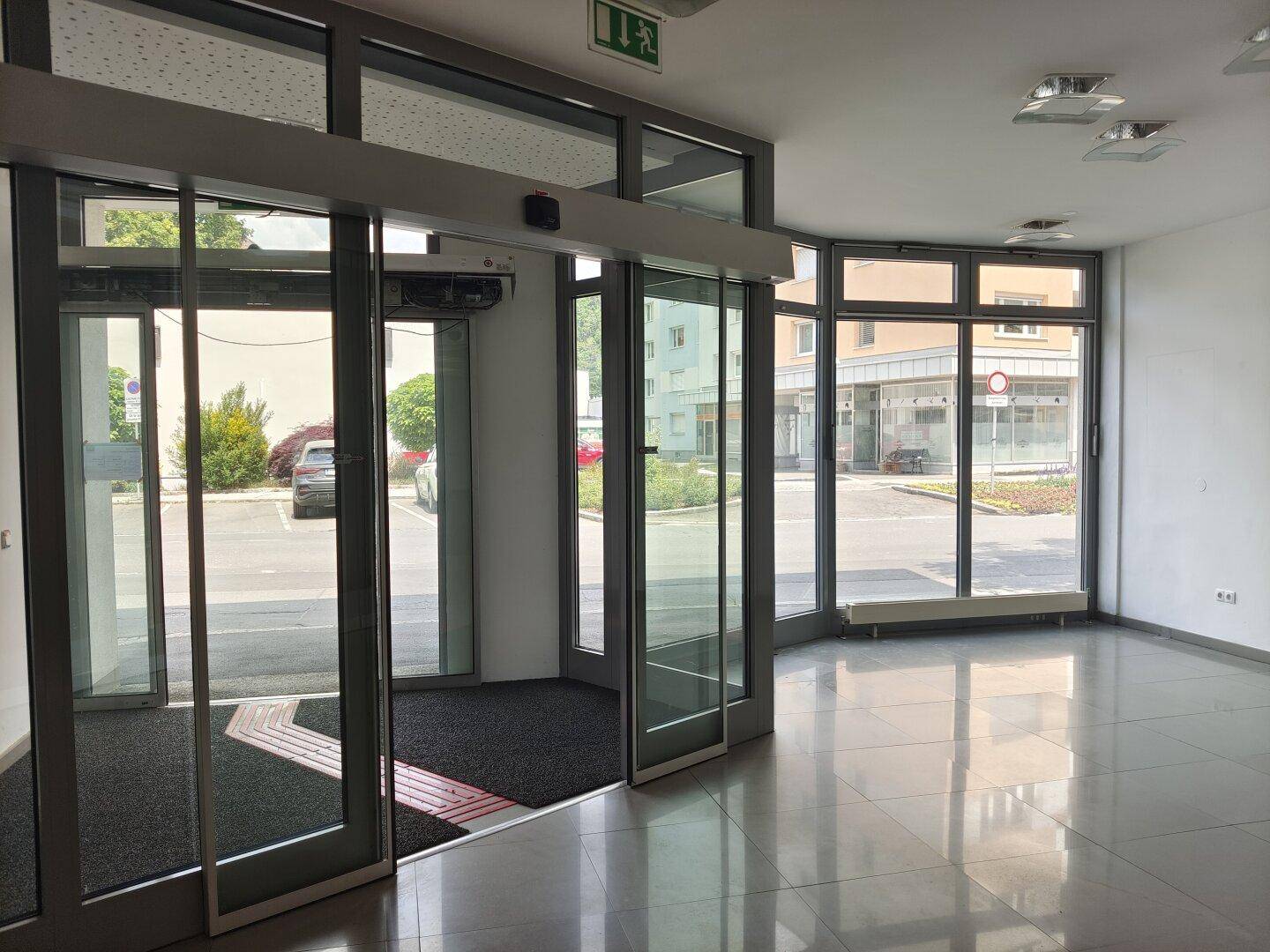 Heller Eingangsbereich mit automatischen Glasschiebetüren und Blick auf die Straße.