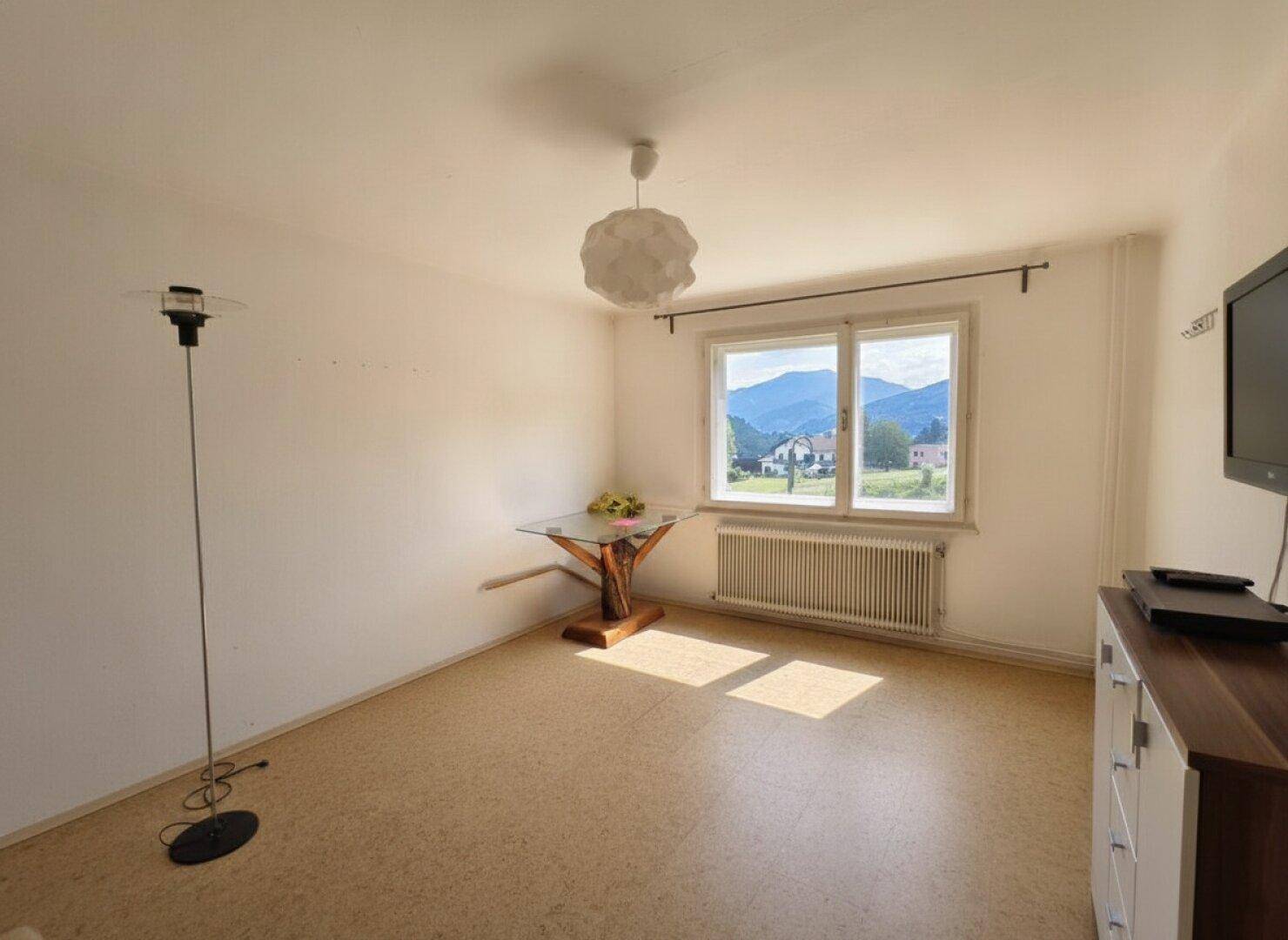 Helles Schlafzimmer mit Korkboden, kleinem Tisch und weitem Bergblick.