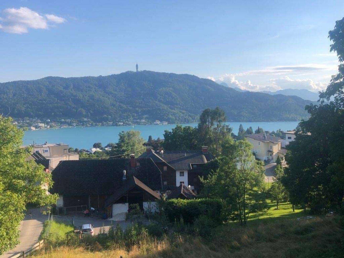 Panoramablick auf eine idyllische Seenlandschaft mit Bergen und ländlicher Bebauung.