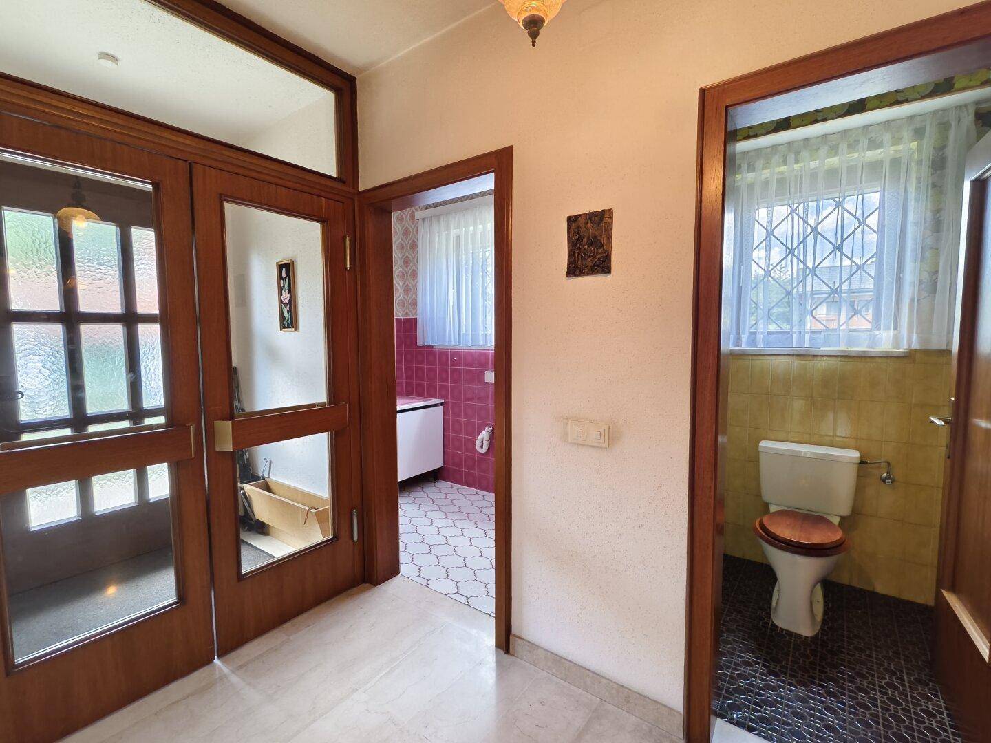 Flur mit Holztüren und Zugang zu einem Badezimmer und einer separaten Toilette.