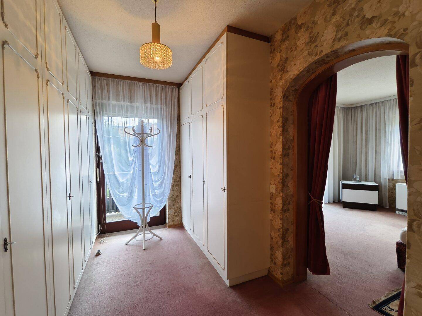 Flur mit Einbauschränken, Teppichboden und Zugang zu einem weiteren Zimmer.