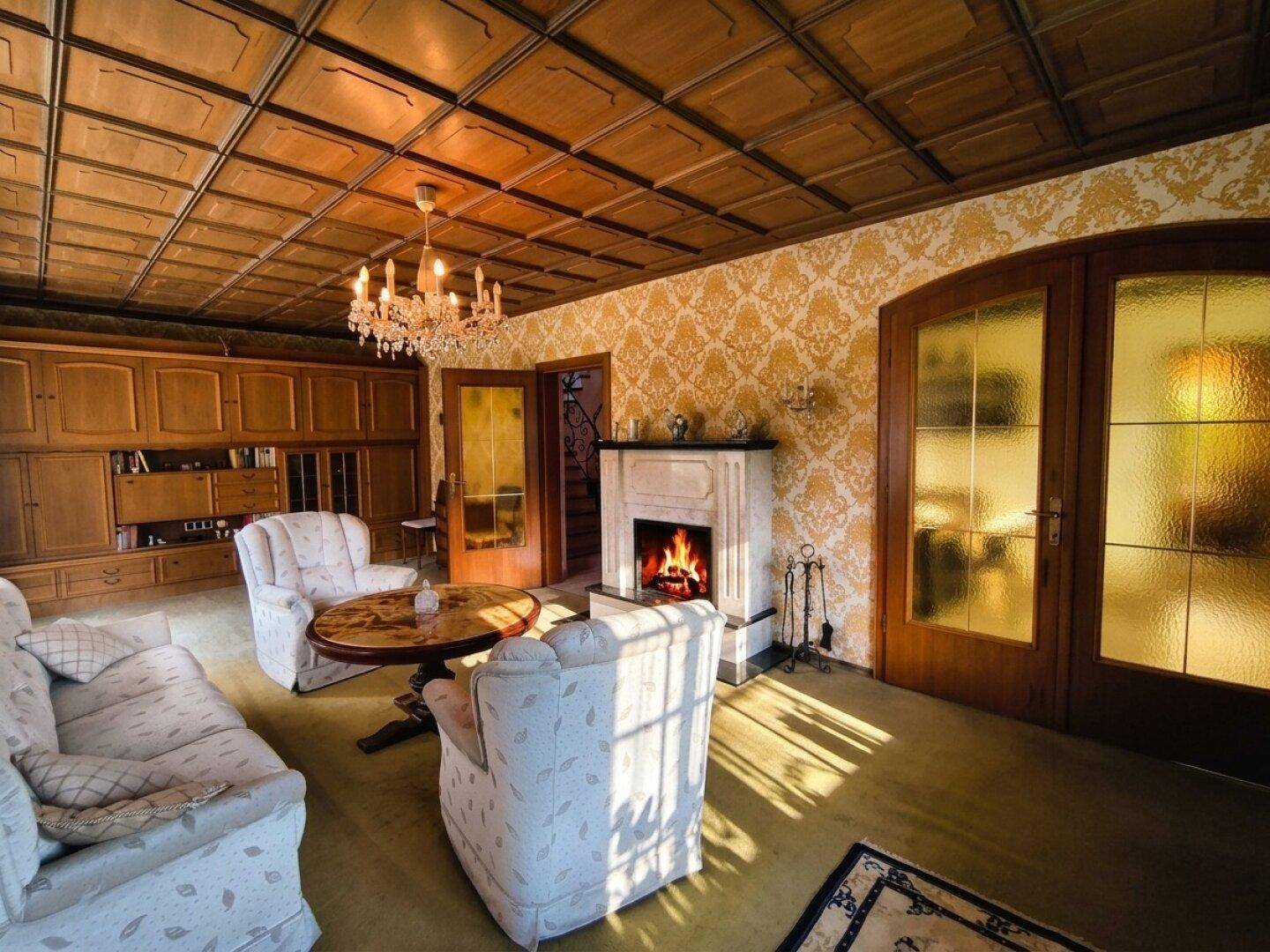 Gemütliches Wohnzimmer mit Holzkassettendecke, Kamin und traditioneller Einrichtung.