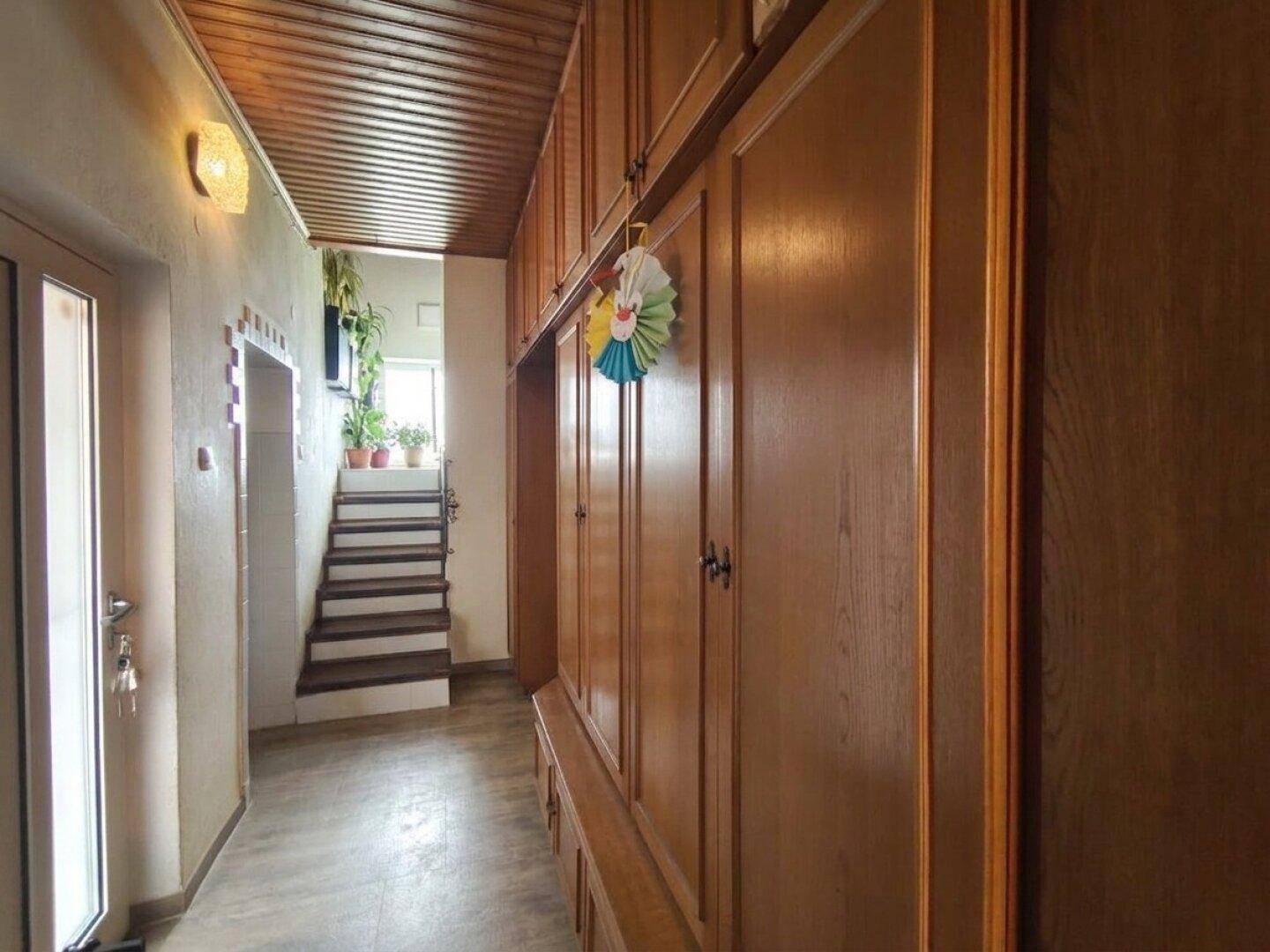 Flur mit eingebauten Holzschränken und einer Treppe, die in die oberen Stockwerke führt.