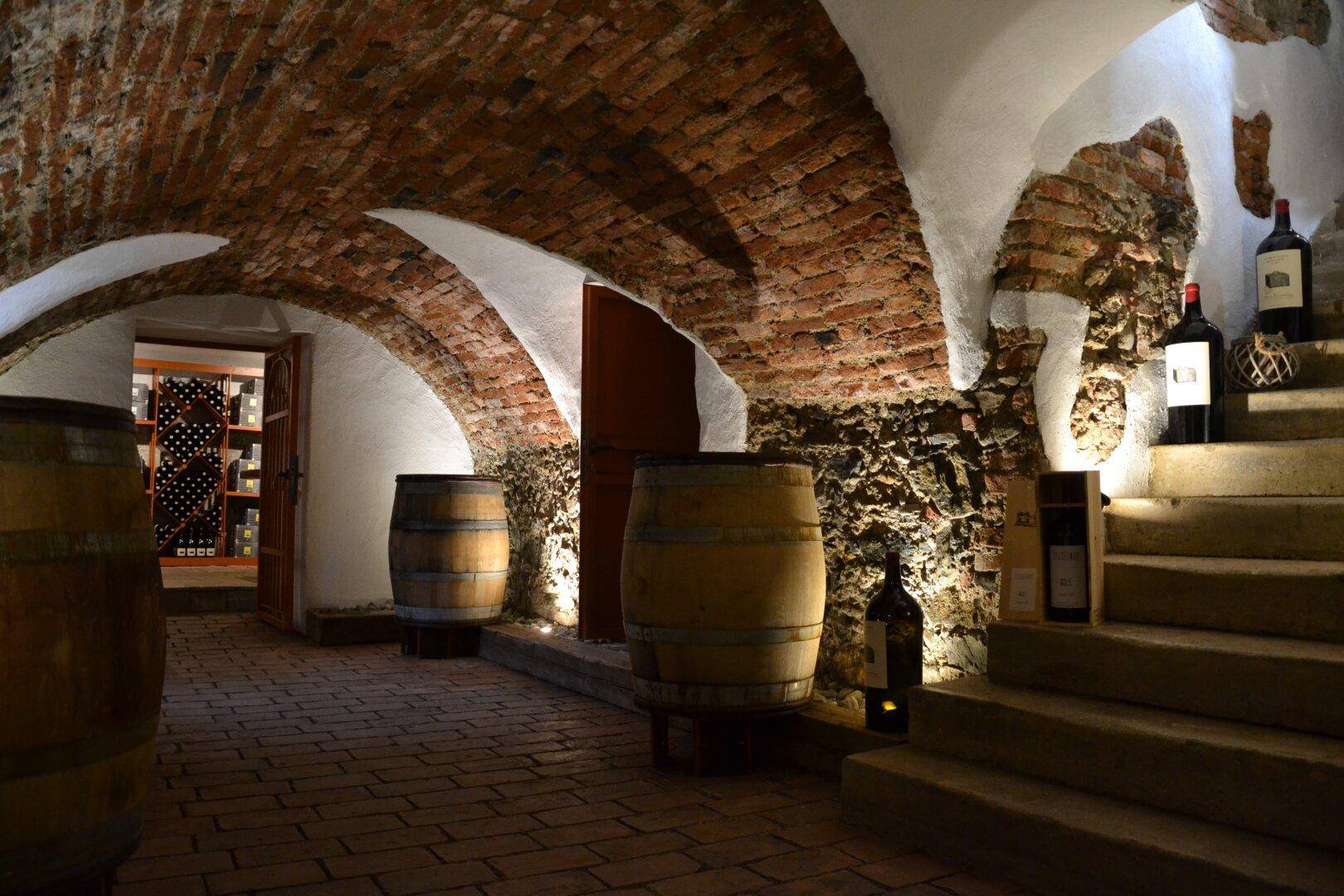 Historischer Weinkeller mit Ziegelgewölbe, Steinmauern und Holzfässern.