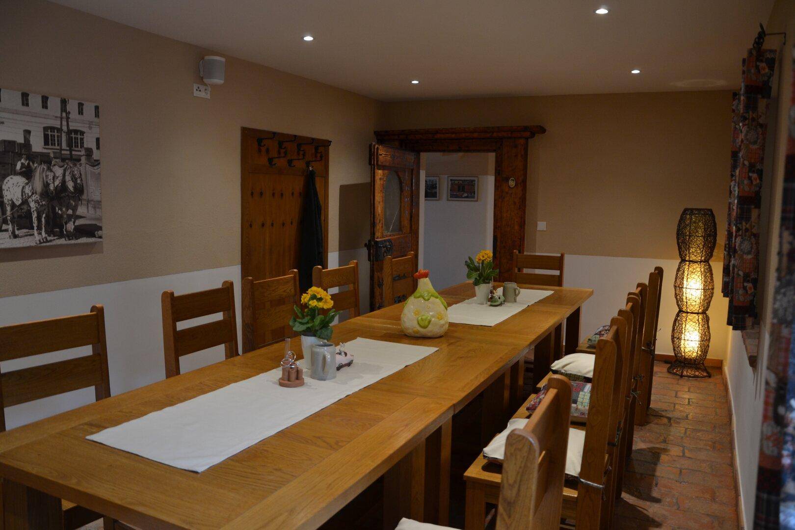 Langer Holztisch mit Stühlen in einem traditionell eingerichteten Speisesaal mit Holztür.