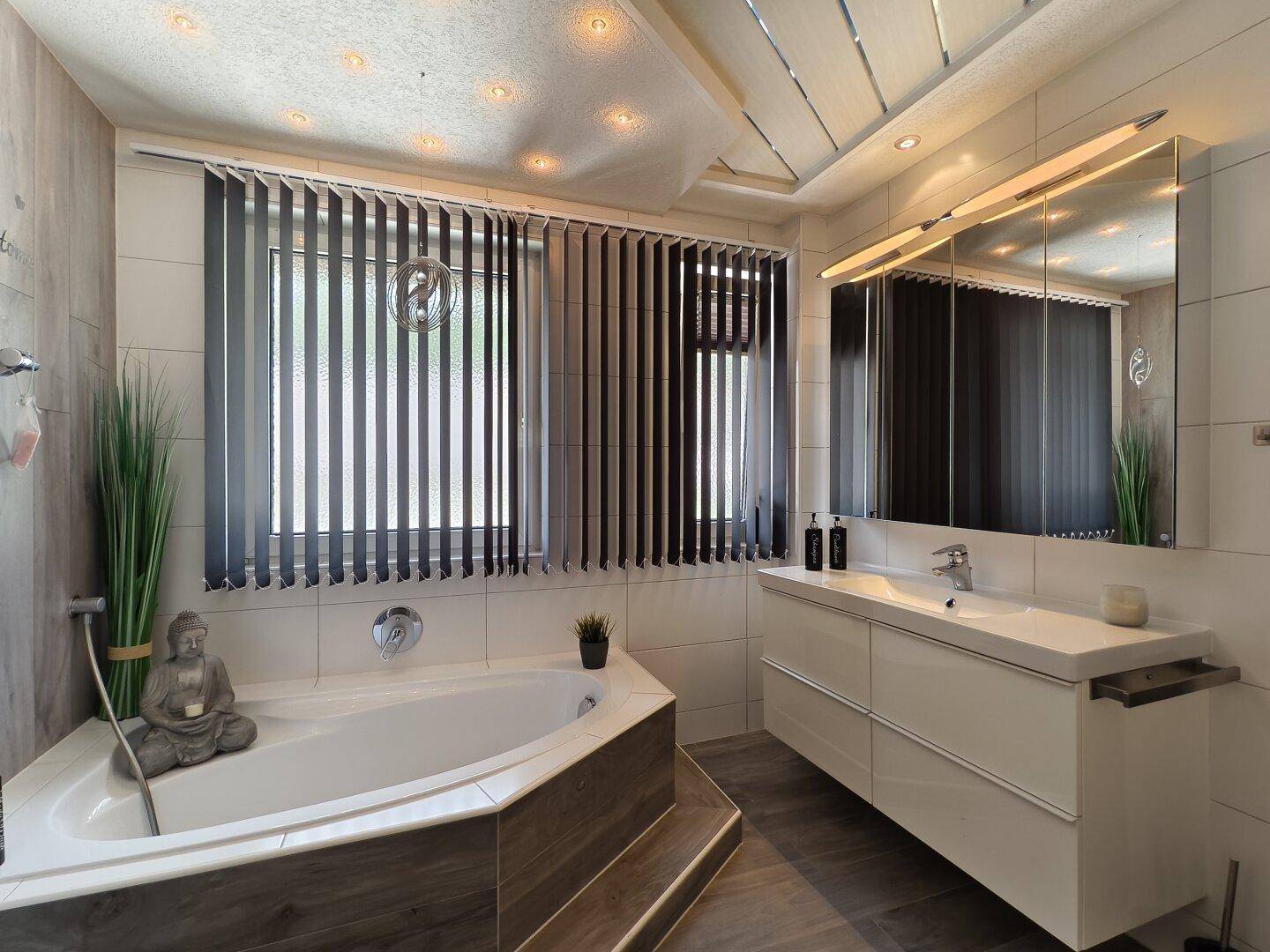 Modernes Badezimmer mit Eckbadewanne, Doppelwaschbecken und Fenster mit Jalousien.