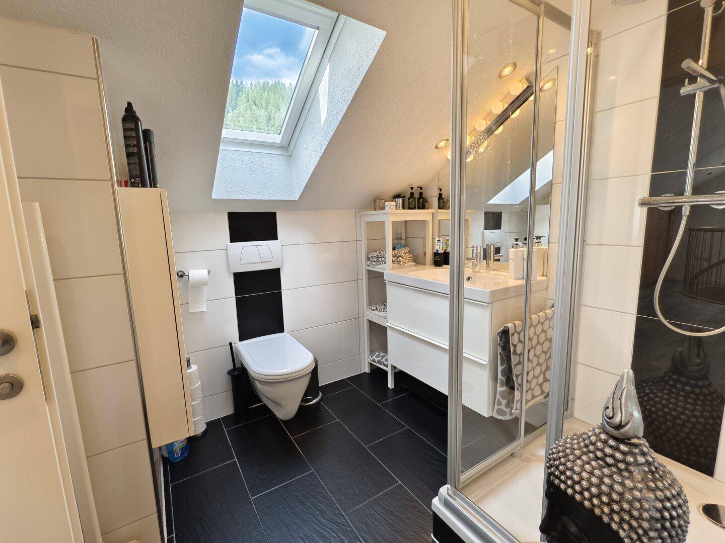 Modernes Badezimmer im Dachgeschoss mit Dachfenster, Dusche und Wand-WC.