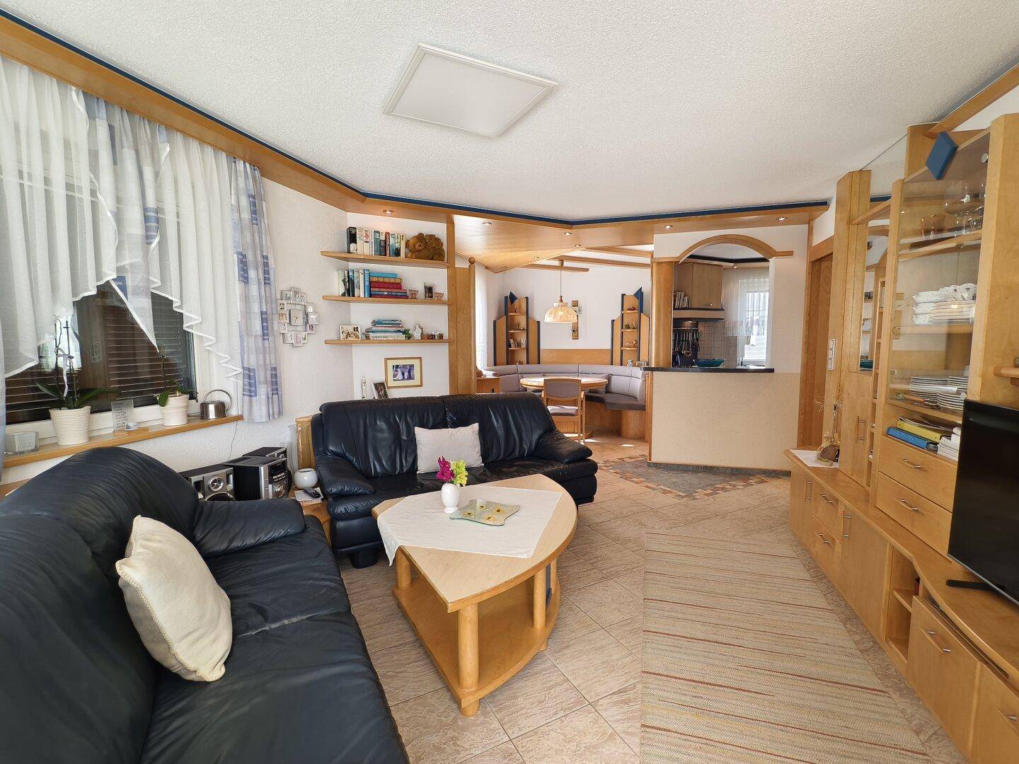 Traditioneller Wohnbereich mit Ledersofas, Holzmöbeln und Blick auf den Essbereich.