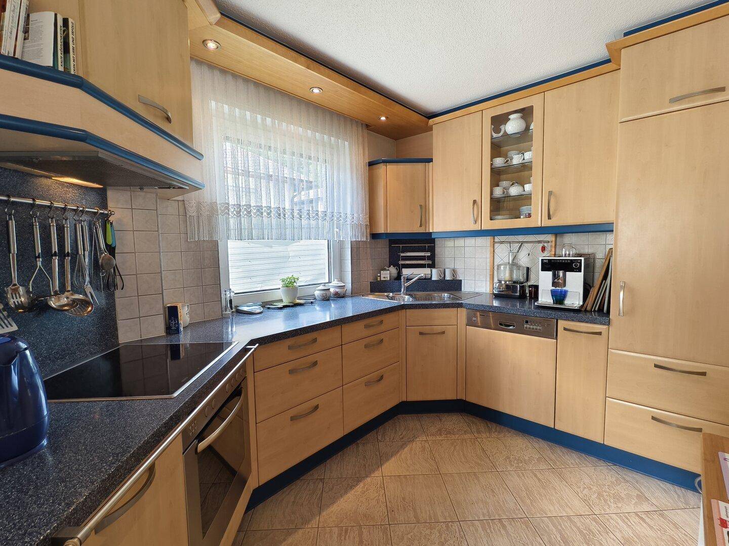 Funktionale Küche mit hellen Holzfronten, blauen Akzenten und modernen Geräten.