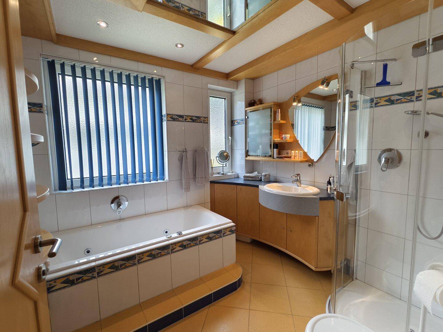Badezimmer mit Badewanne, Duschkabine, Einzelwaschbecken und Fenster.