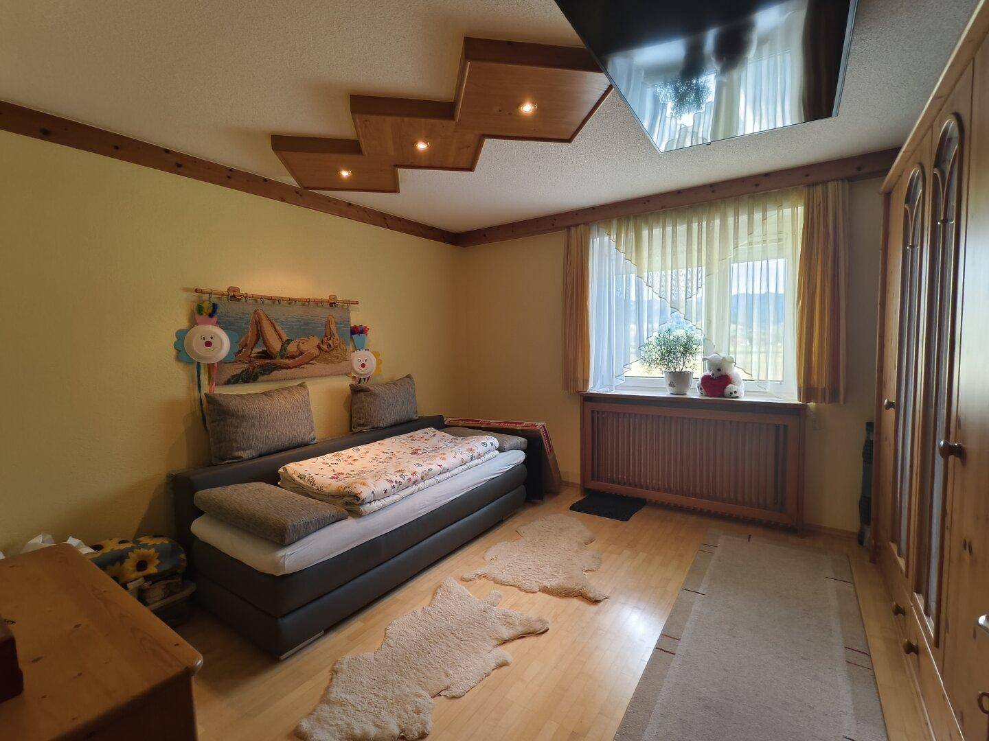 Gemütliches Schlafzimmer mit Einzelbett, Holzmöbeln und Fenster.