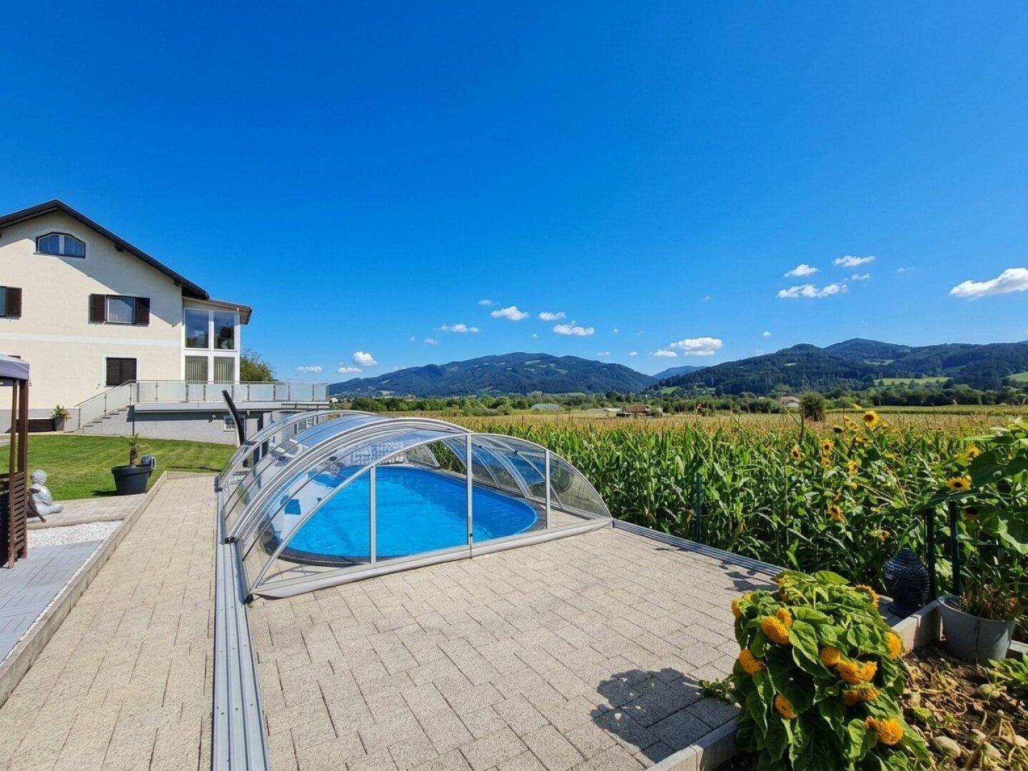 Weitläufige Terrasse mit Pool und Blick auf die umliegenden Felder und Berge.