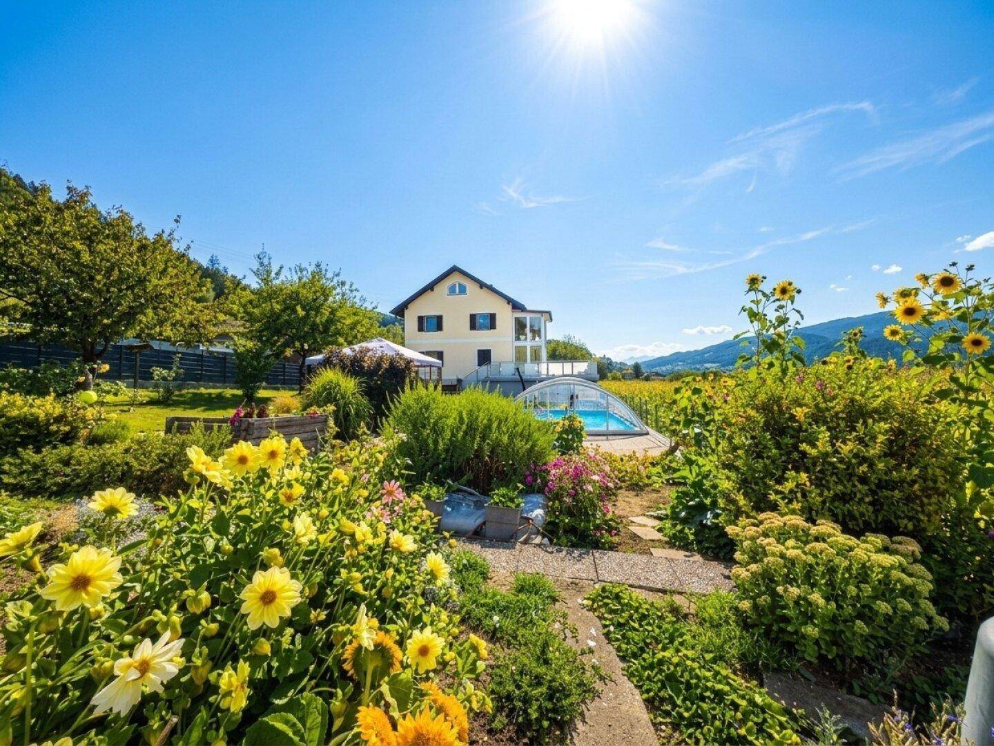 Farbenprächtiger Blumengarten mit Blick auf das Wohnhaus, den Pool und die weiten Felder.