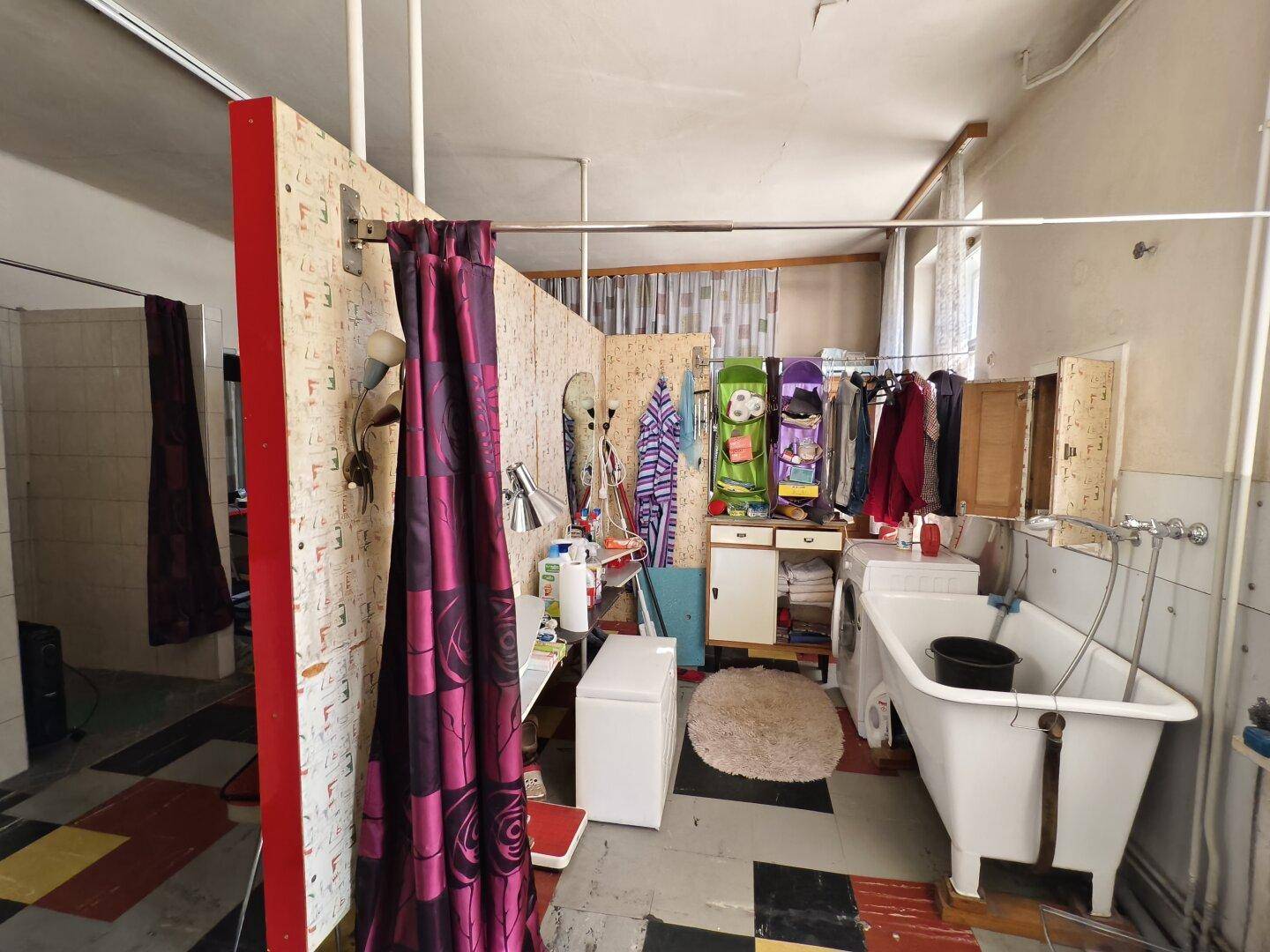 Einfaches Badezimmer mit Badewanne, Duschvorhang und farbigen Fliesen im Retro-Stil.