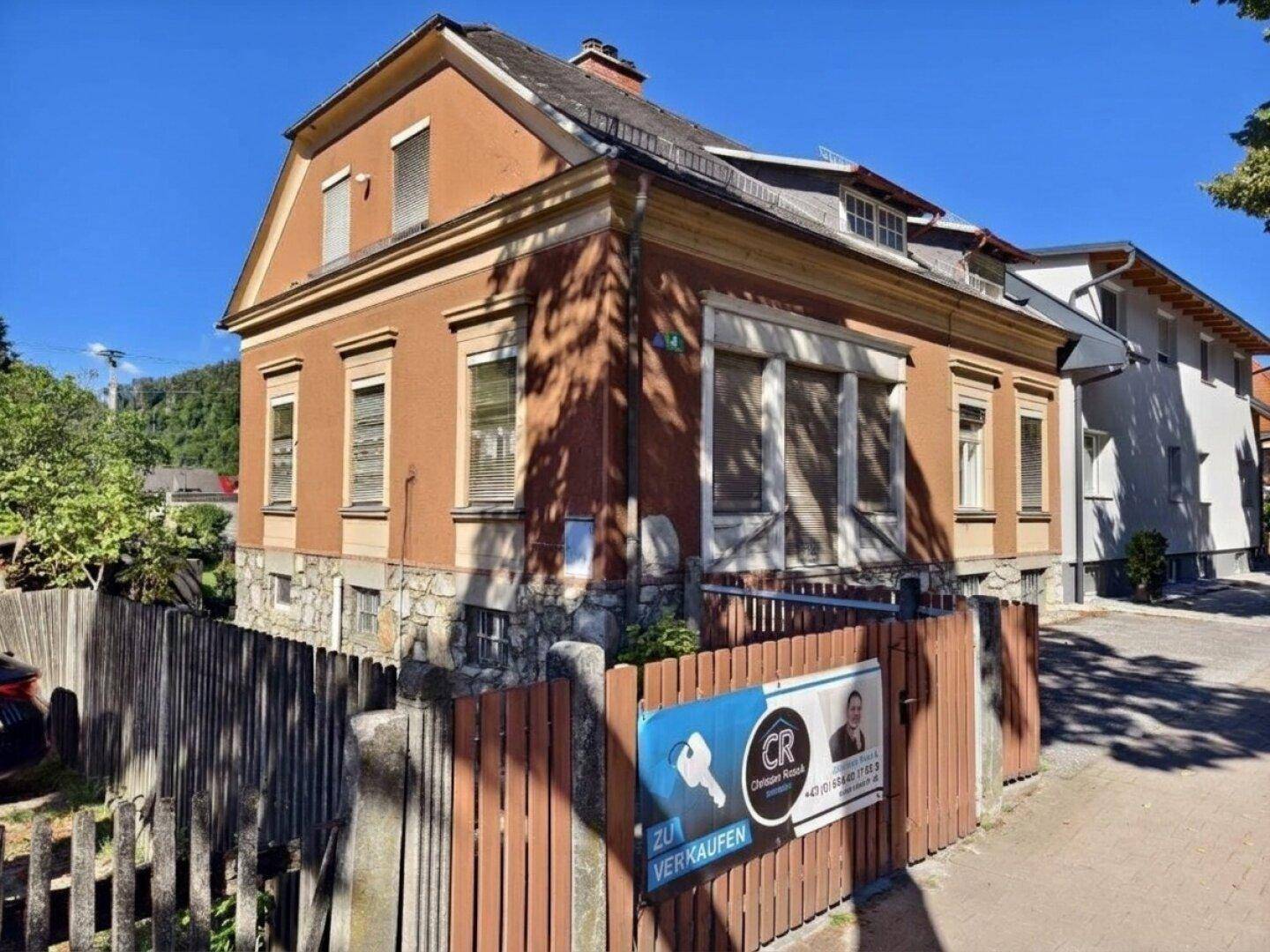 Seitenansicht des historischen Gebäudes mit traditioneller Architektur und Holzzaun.